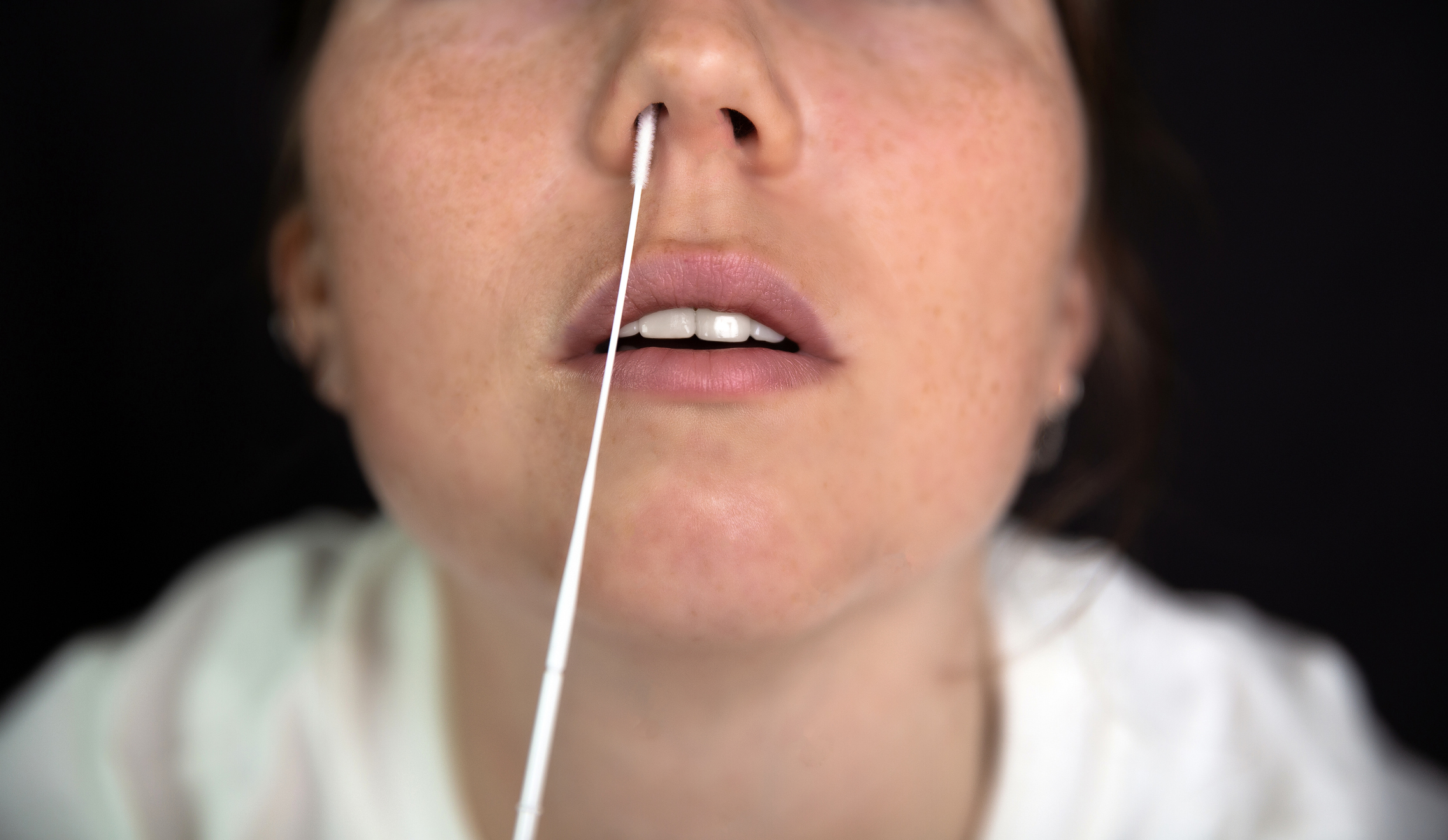Close-Up Woman Inserting Cotton Swab In Nose