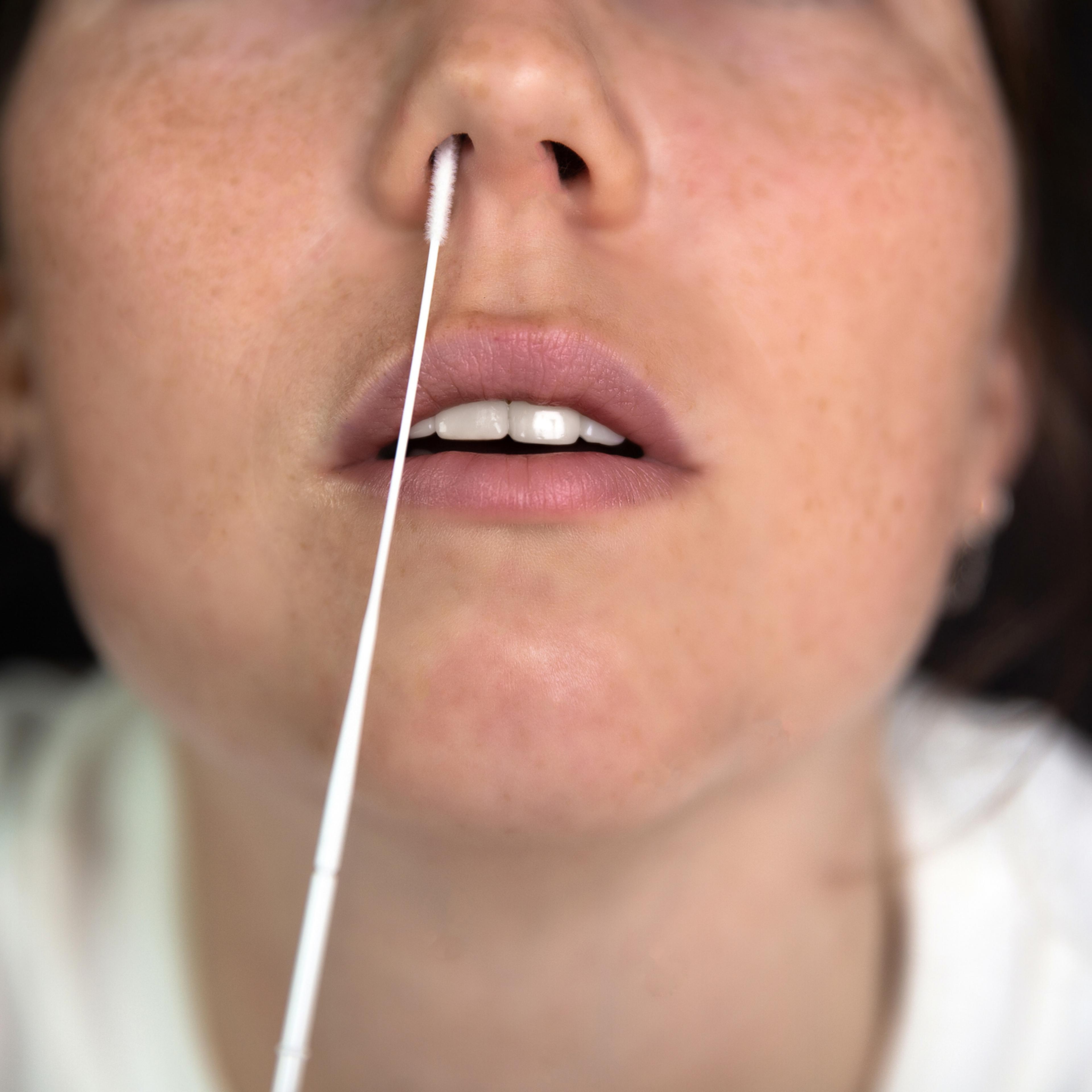 Close-Up Woman Inserting Cotton Swab In Nose