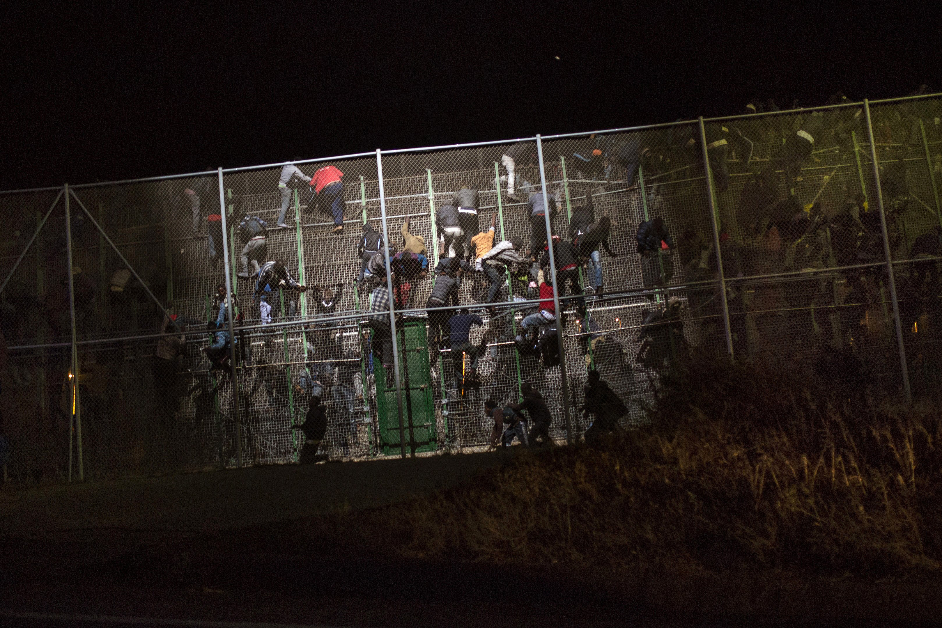 Sub-Saharan migrants scale a metallic fence that divides Morocco and the Spanish enclave of Melilla, early on May 28, 2014.