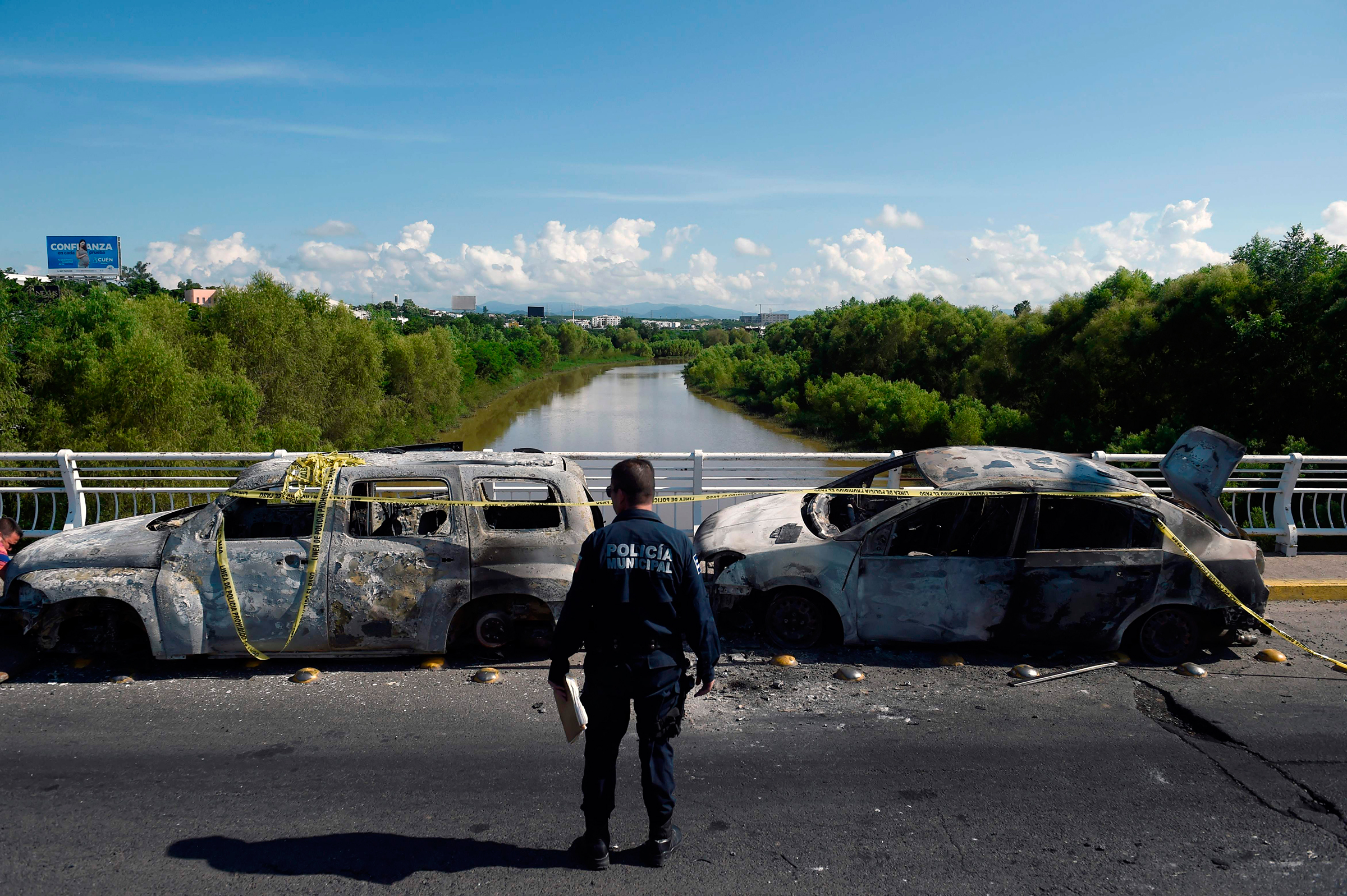 A policeman stands next to burnt vehicles after heavily armed gunmen had waged an all-out battle against Mexican security forces in Culiacan, Mexico.