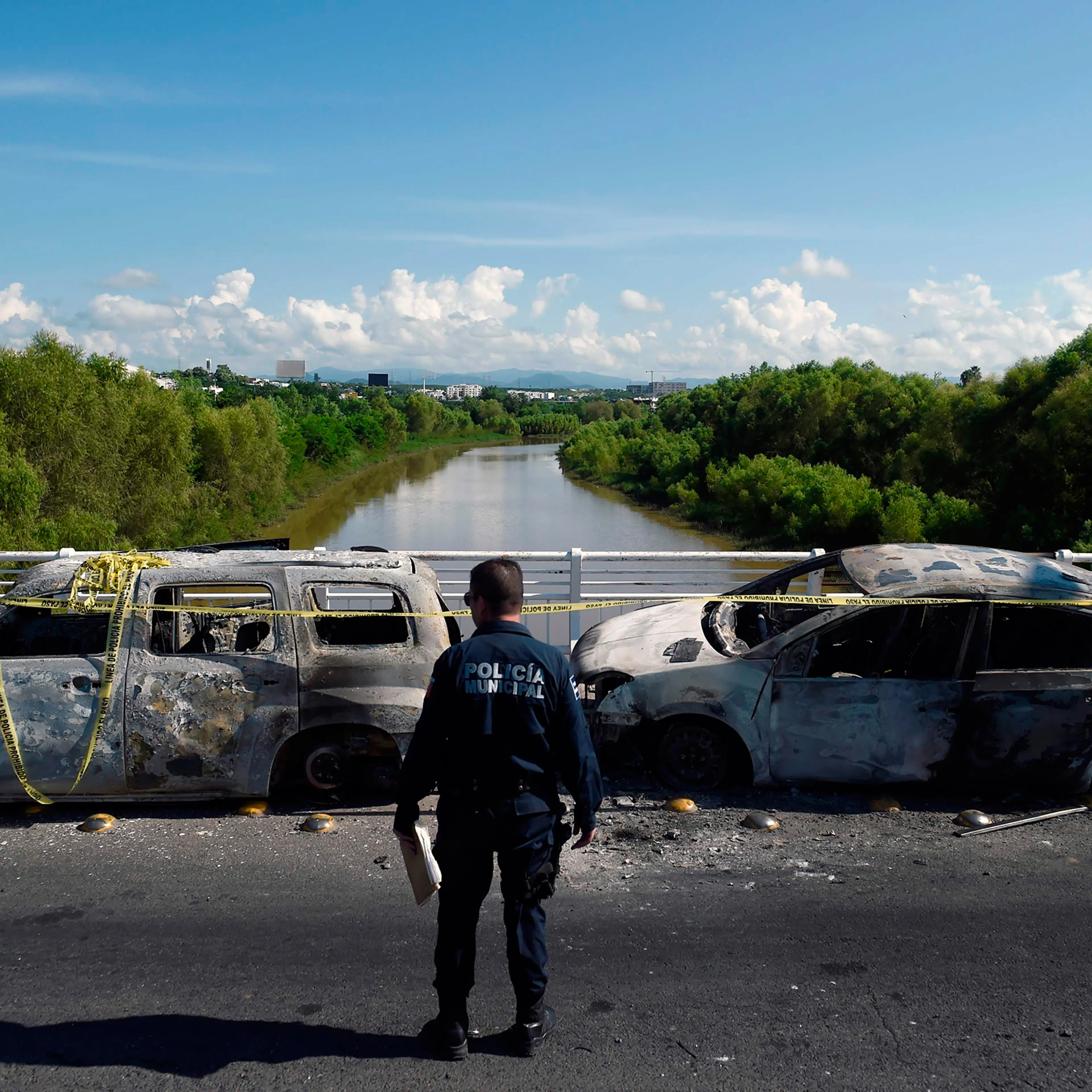 A policeman stands next to burnt vehicles after heavily armed gunmen had waged an all-out battle against Mexican security forces in Culiacan, Mexico.