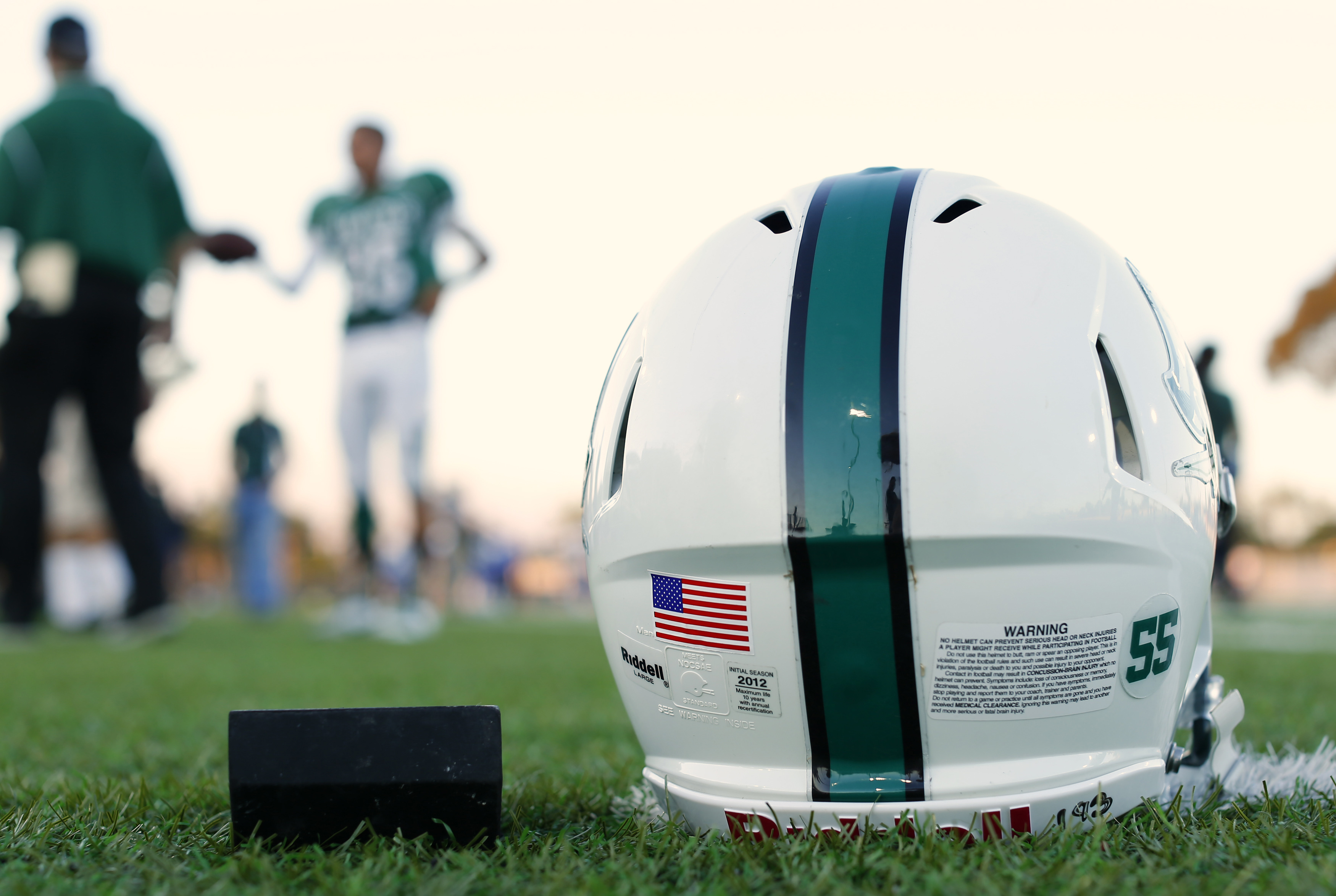 A football helmet's health warning sticker is pictured between a U.S. flag and the number 55, in memory of former student and NFL player Junior Seau, as the Oceanside Pirates high school football team prepares for their Friday night game in Oceanside