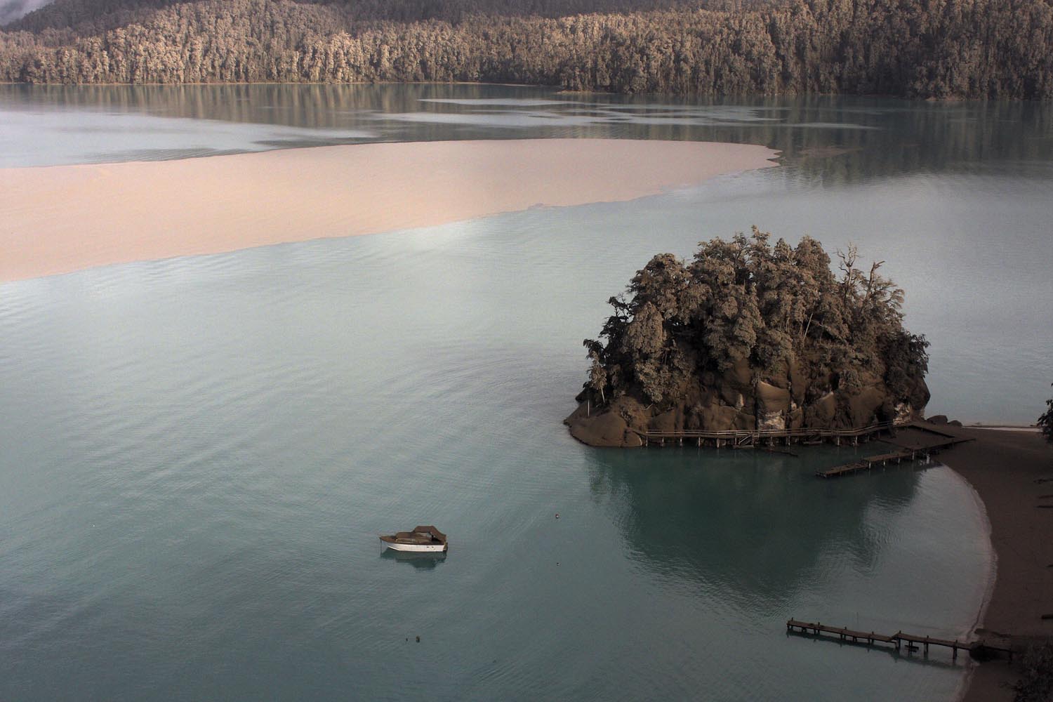 A boat moored in Puerto Arauco, at the Nahuel Huapi Lake and the landscape around are seen covered with sand and volcanic from the Chilean Puyehue-Cordon Caulle volcano in Villa La Angostura, southern Argentina, Friday, June 17, 2011. 