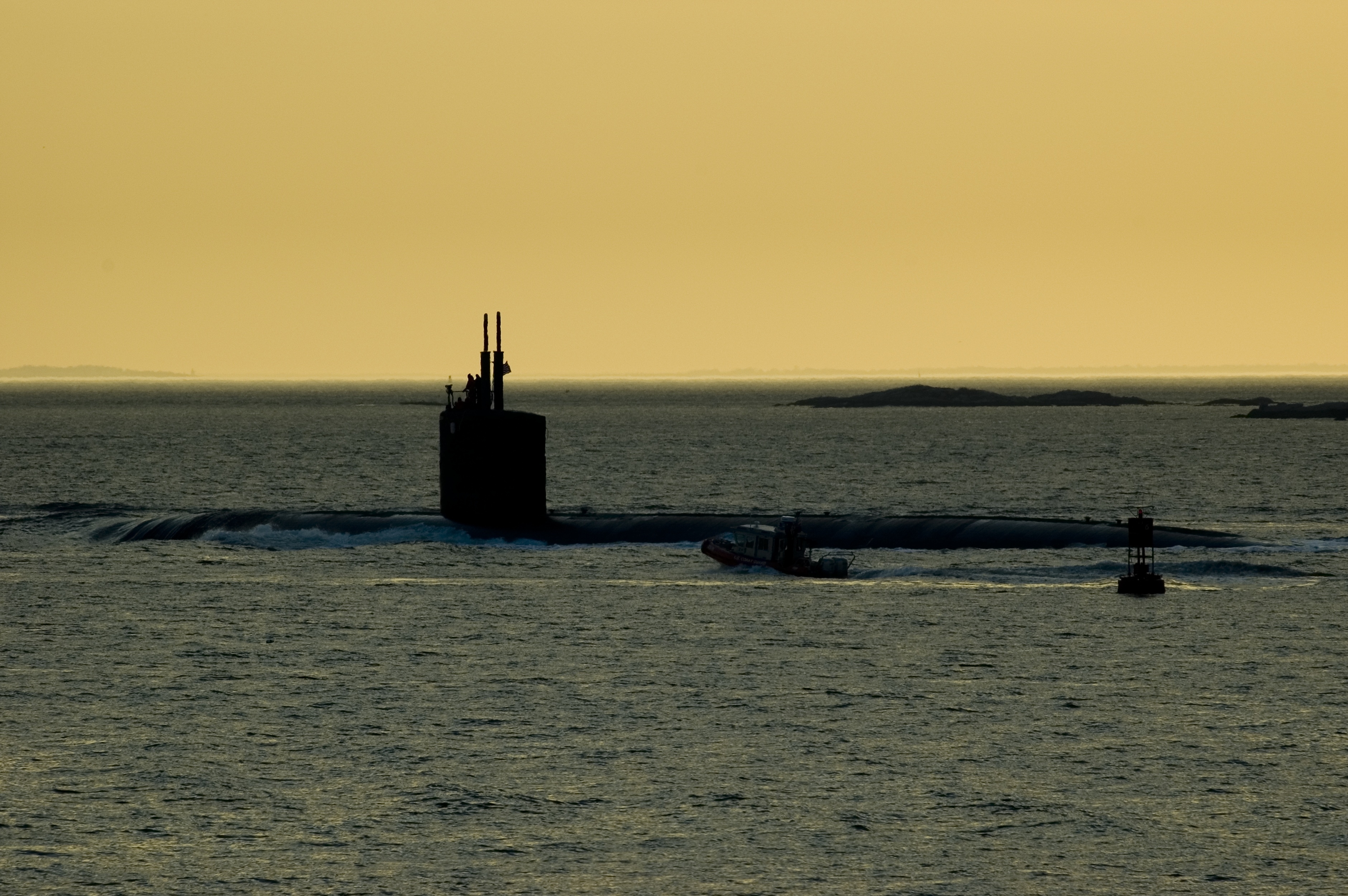 Silhouette of a submarine being followed by a coast guard zodiac.