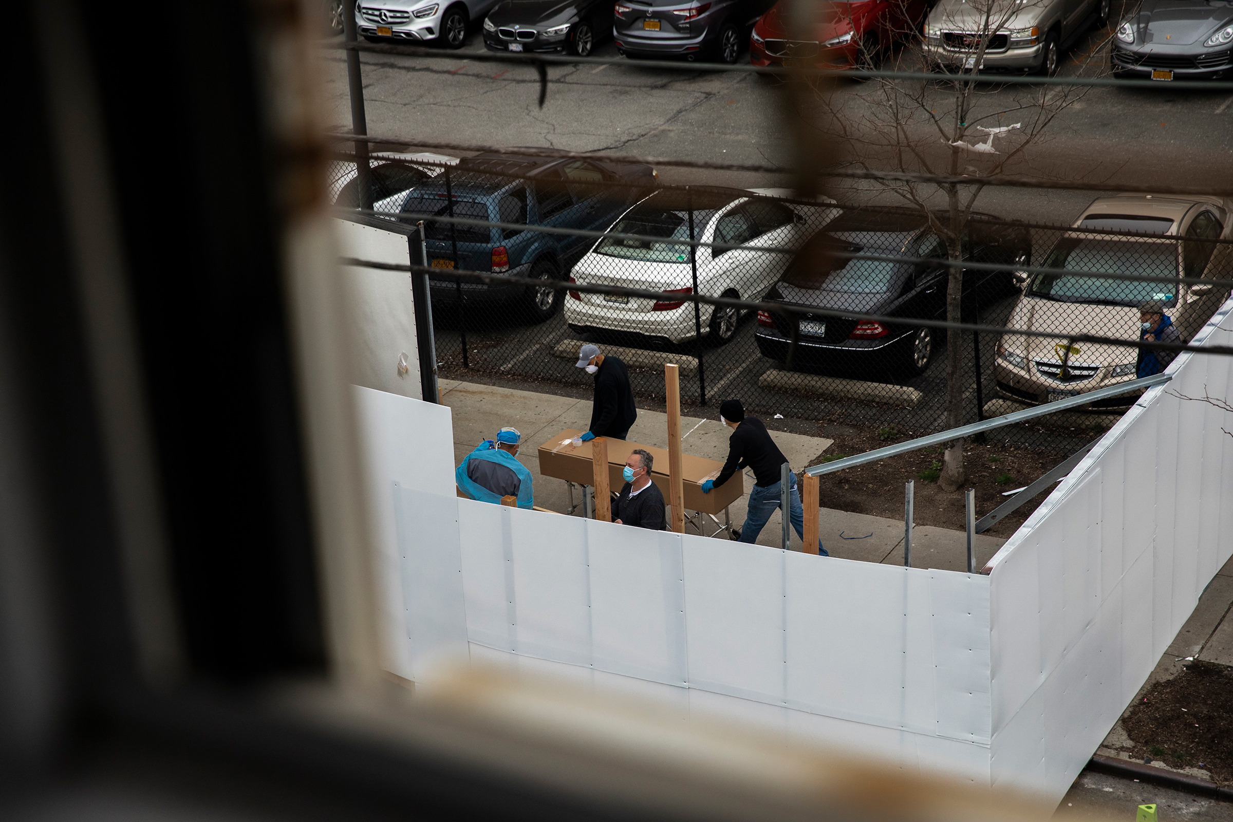 Workers transport a casket-sized box near the refrigerated morgue truck outside Wyckoff Heights Medical Center in Brooklyn on March 30, 2020.