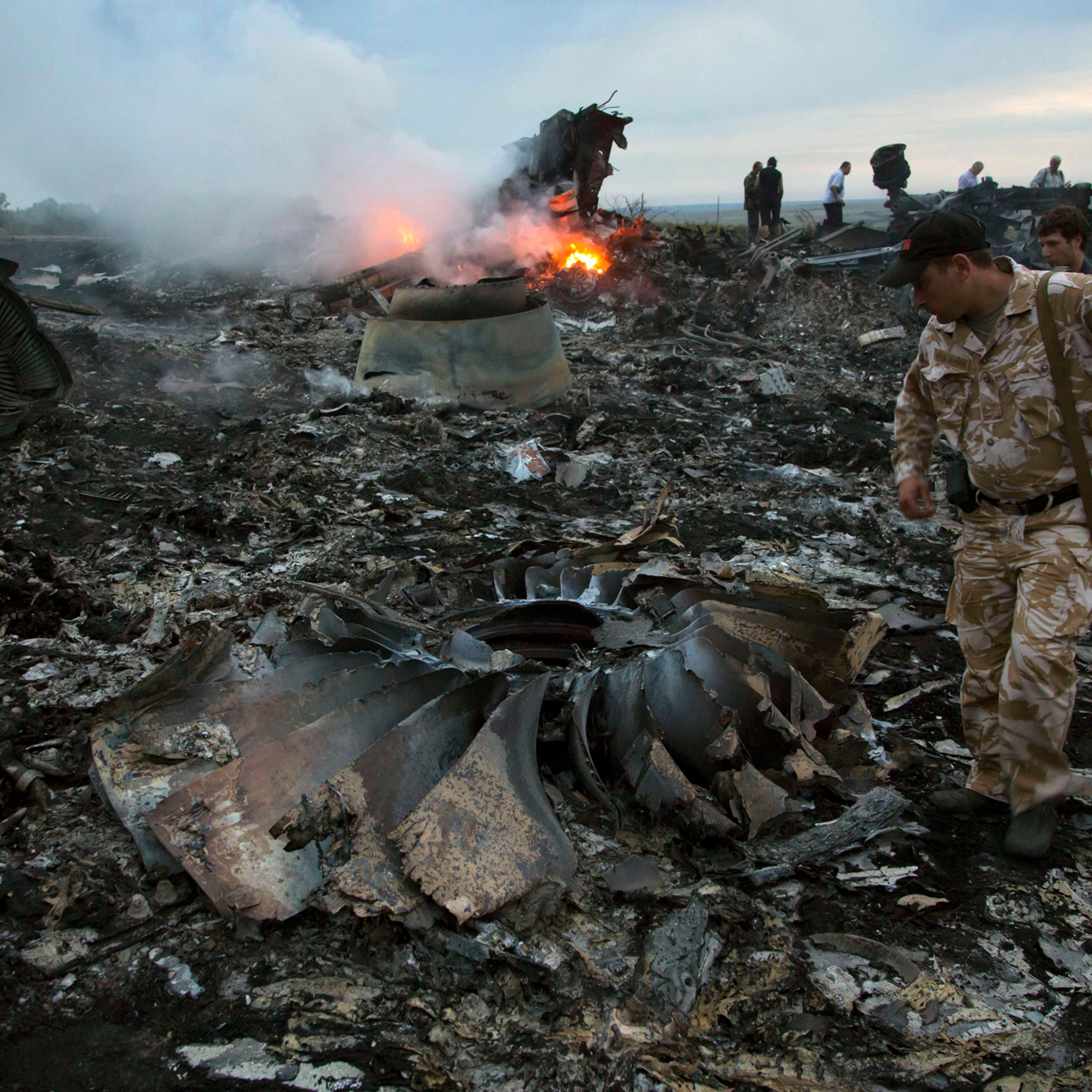 People walk amongst the debris at the crash site of a passenger plane near the village of Grabovo, Ukraine, July 17, 2014.