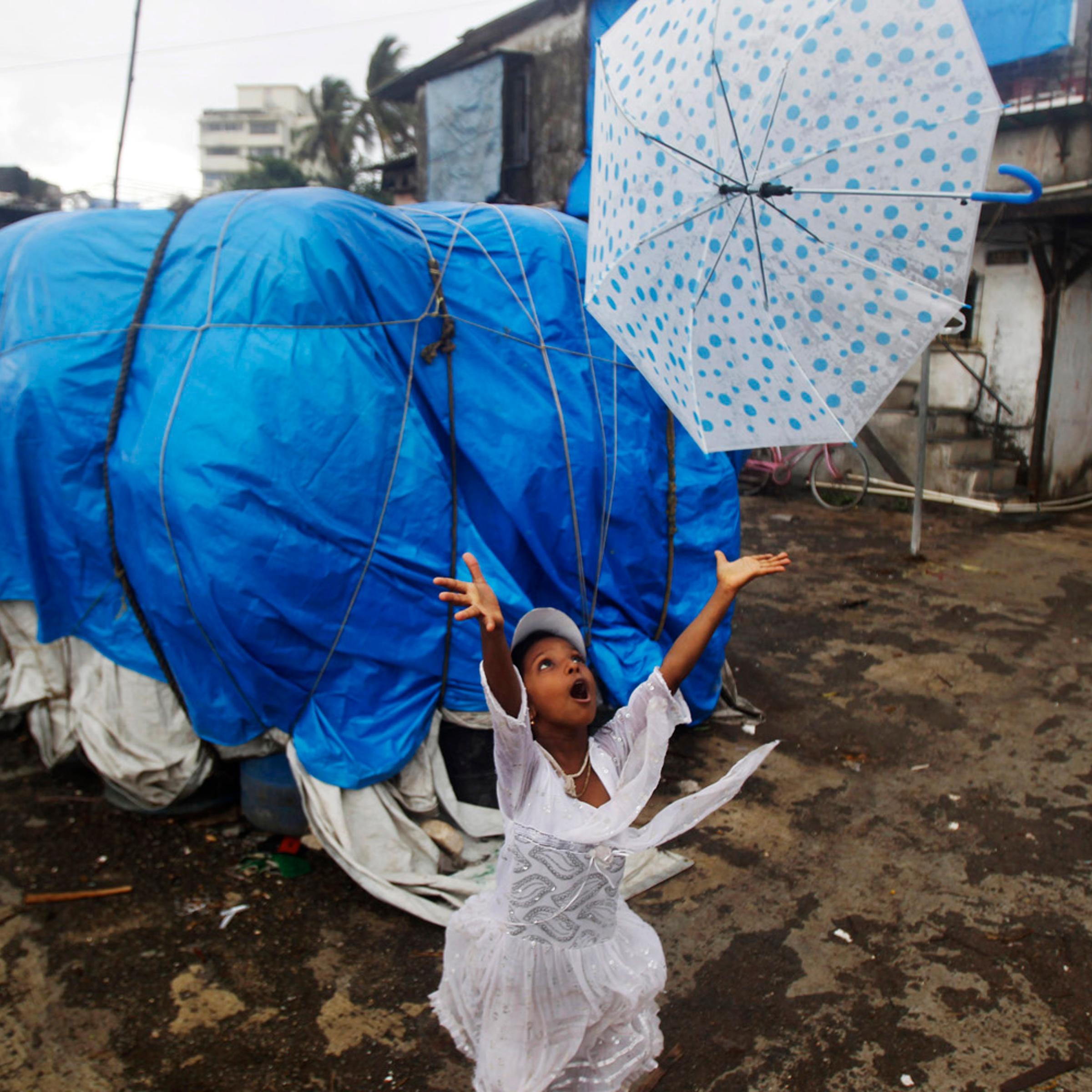 June 17, 2012. A girl tries to recover her umbrella blowing away in the wind in Mumbai.