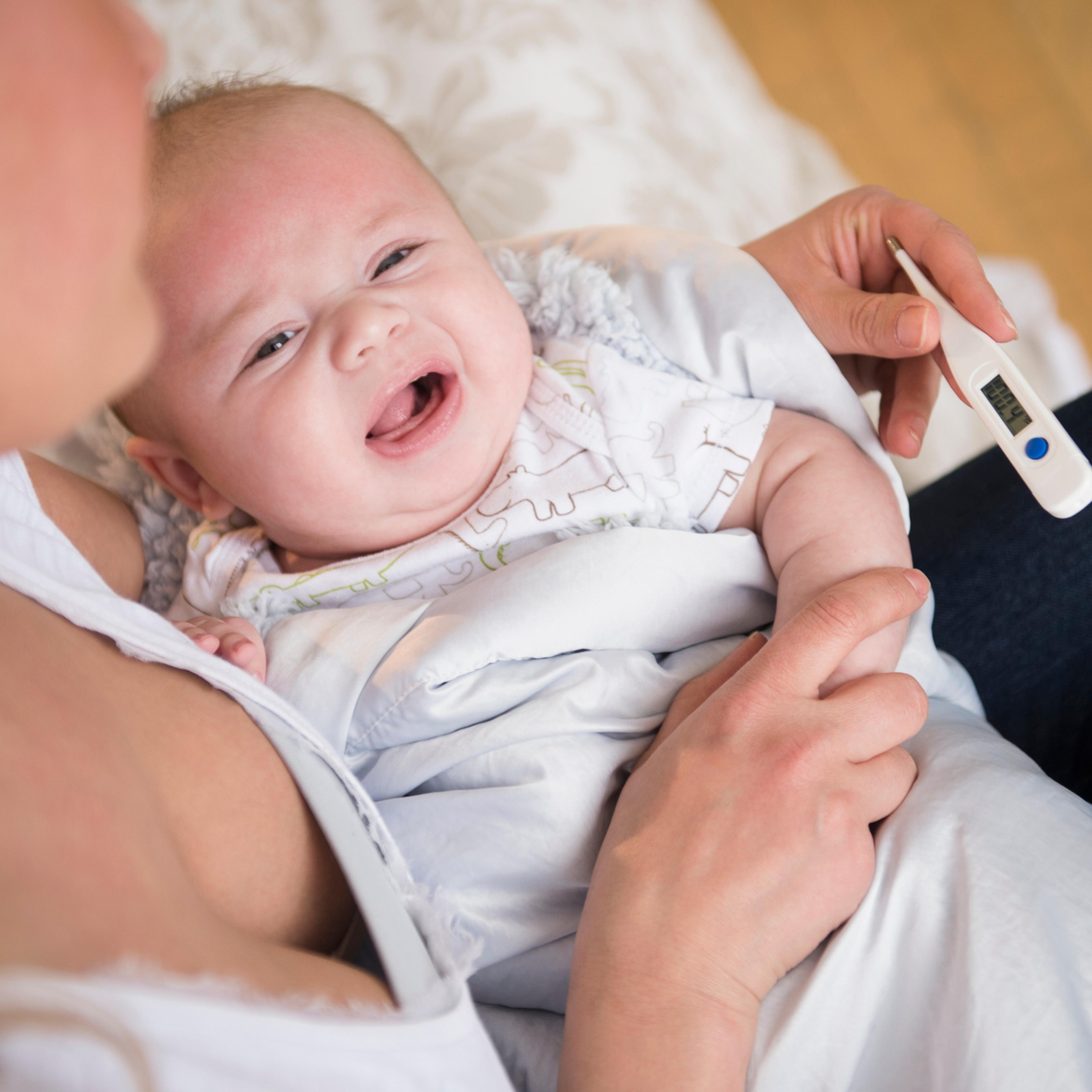 Caucasian mother taking crying baby's temperature