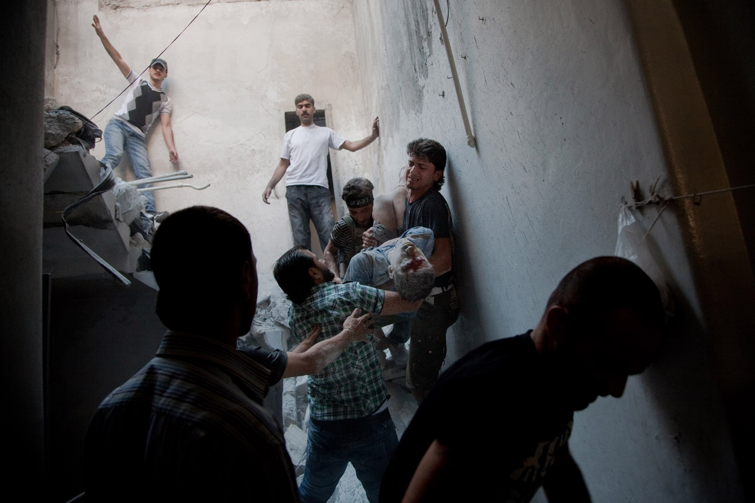 <i>All photographs were taken on Aug. 6, 2012</i><br>
Men carry Hatem Qureya, 15, after he was trapped under rubble following an airstrike in the neighborhood of Bustan al-Qasr in Aleppo, Syria