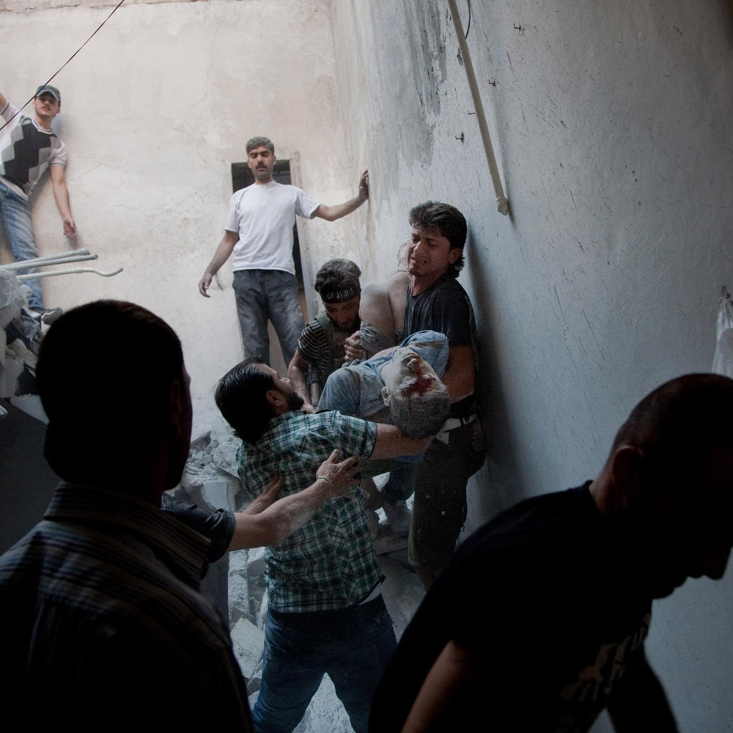 <i>All photographs were taken on Aug. 6, 2012</i><br>
Men carry Hatem Qureya, 15, after he was trapped under rubble following an airstrike in the neighborhood of Bustan al-Qasr in Aleppo, Syria