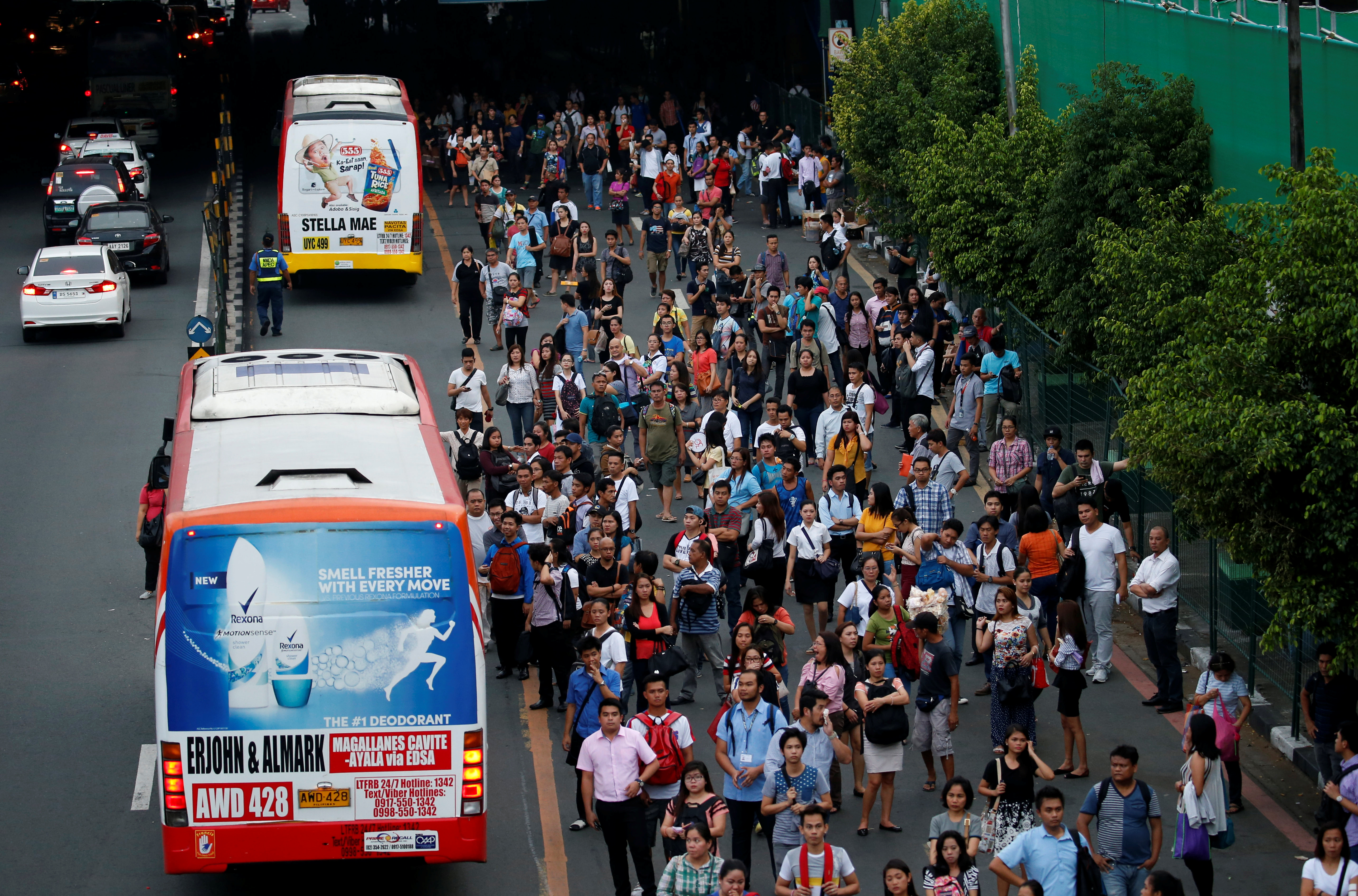 Commuters wait for their ride at a bus stop during rush hours along main highway EDSA in Makati, Metro Manila