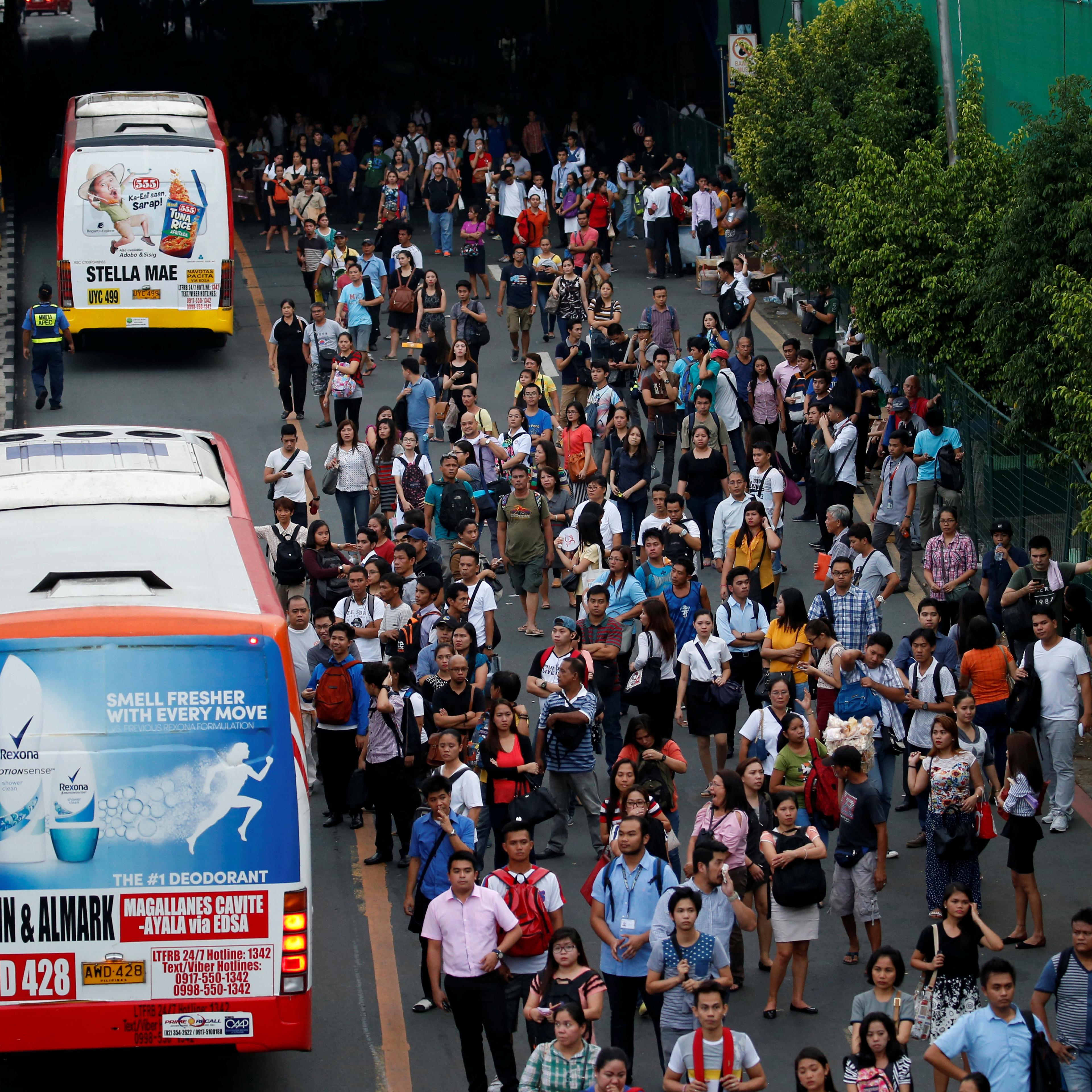 Commuters wait for their ride at a bus stop during rush hours along main highway EDSA in Makati, Metro Manila