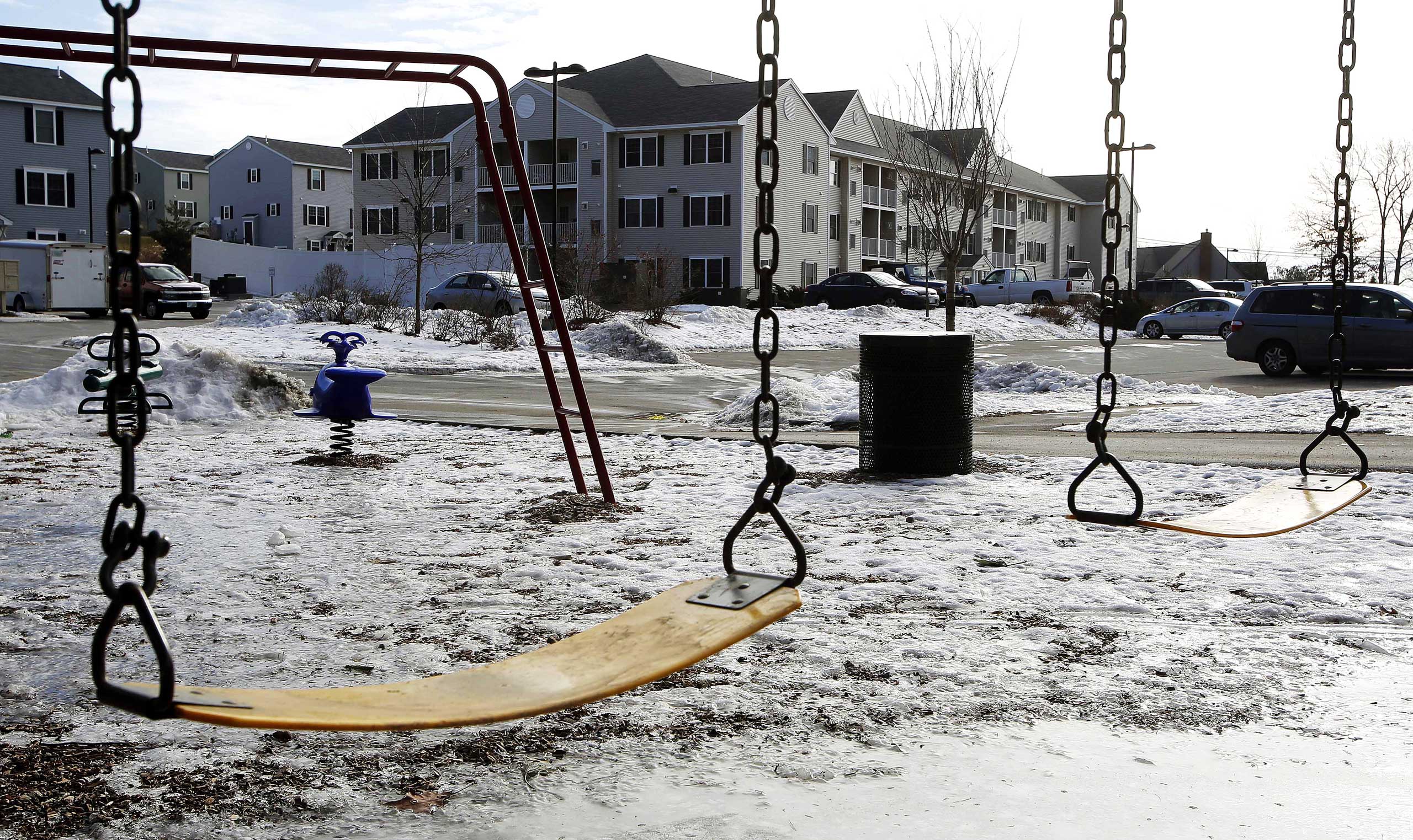 An empty playground is seen at an apartment complex, Jan. 22, 2015, in Manchester, N.H. where authorities say twin 9-year-old boys were left mostly alone for four months after their parents took three siblings to Nigeria and left an uncle to care for the