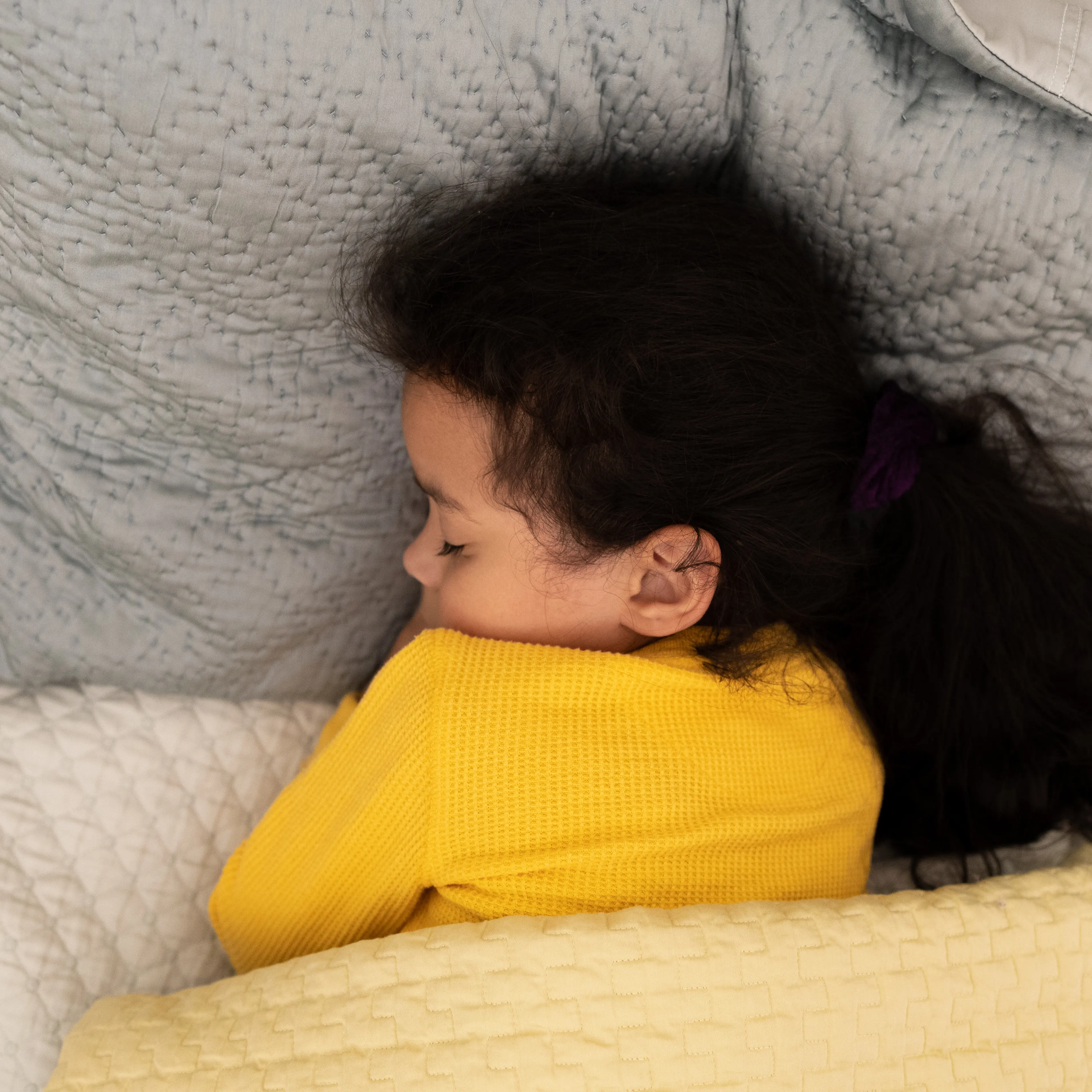young mixed-race girl soundly sleeping under weighted blanket