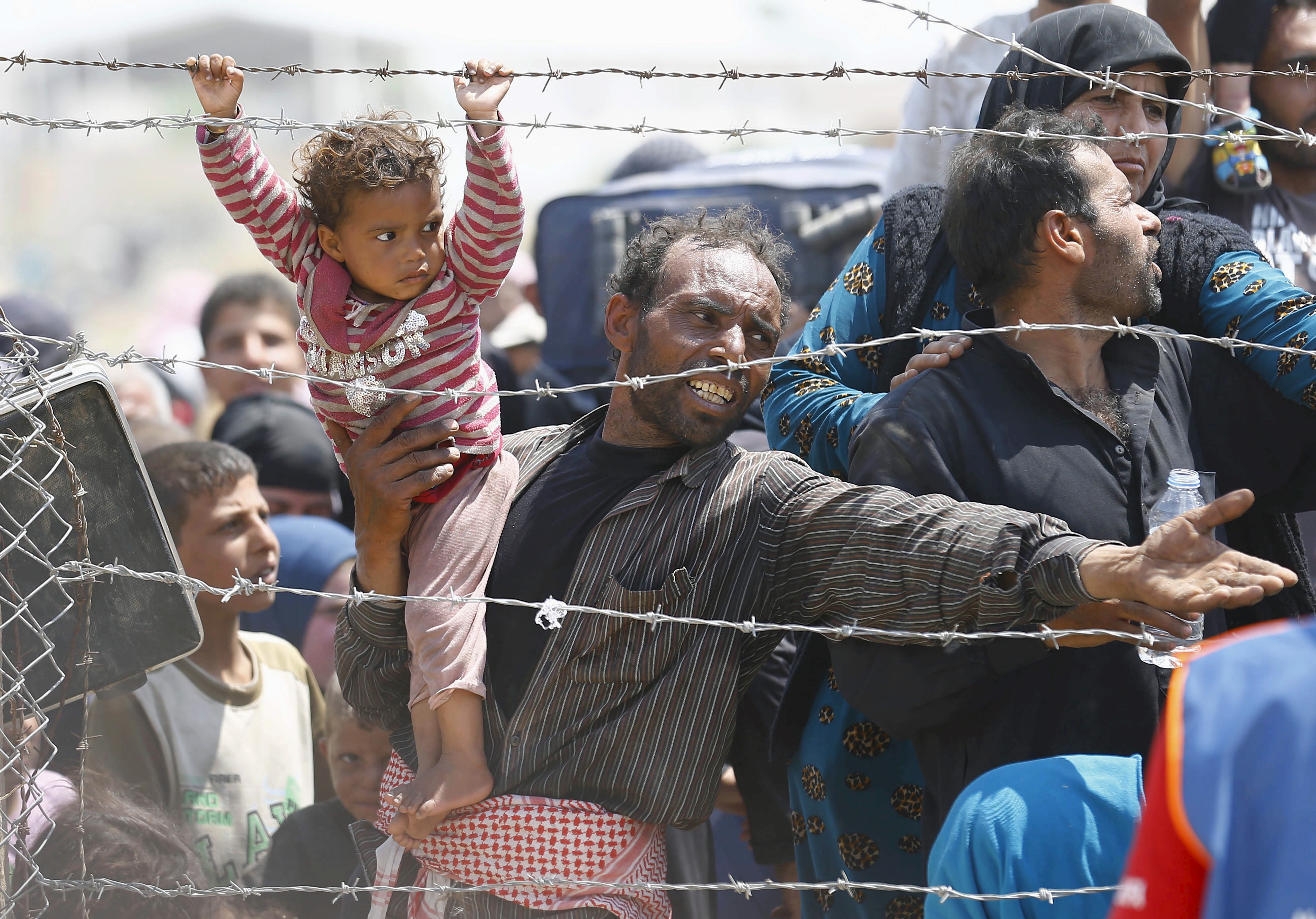 A Syrian refugee reacts as he waits behind border fences to cross into Turkey at Akcakale border gate in Sanliurfa province, Turkey, June 15, 2015.