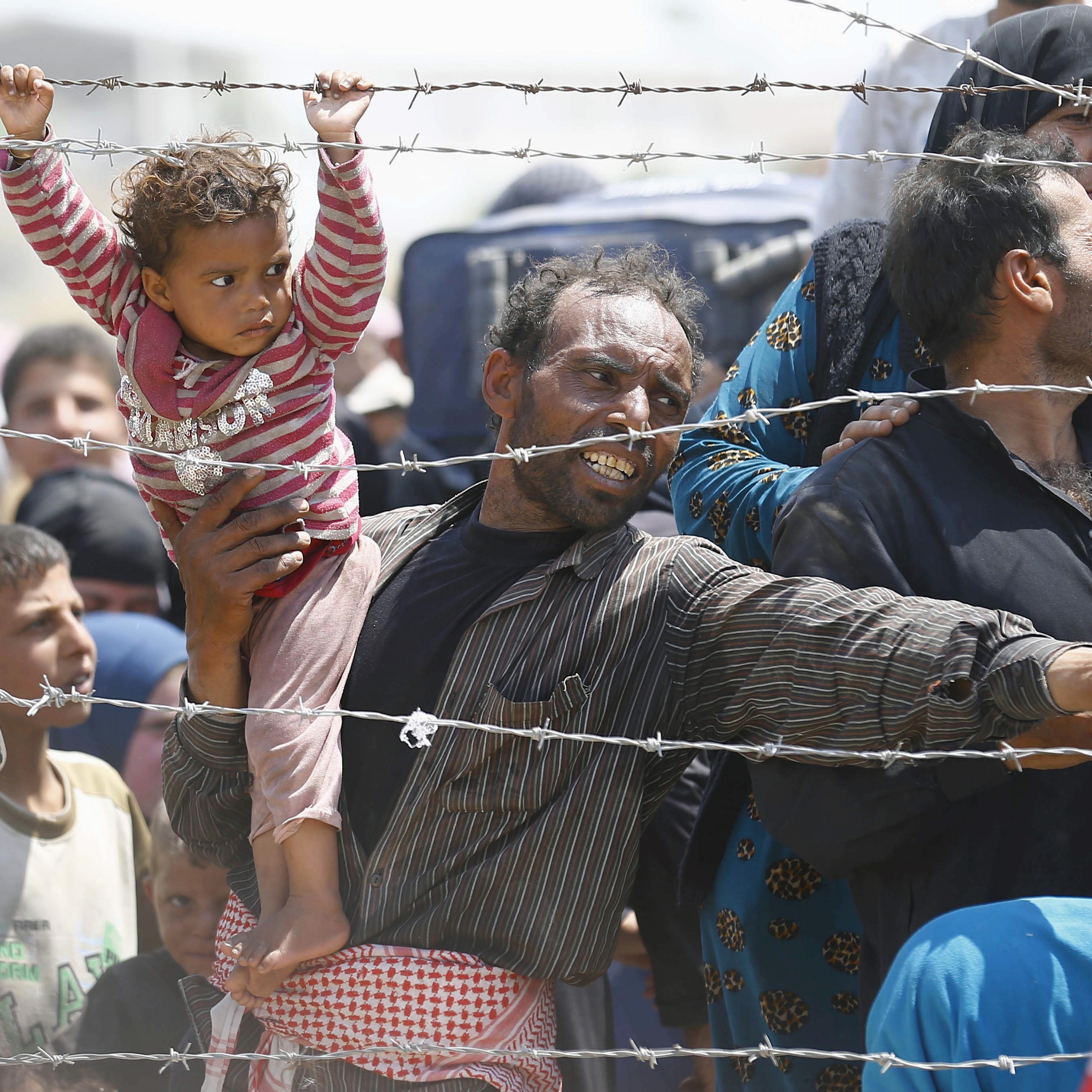 A Syrian refugee reacts as he waits behind border fences to cross into Turkey at Akcakale border gate in Sanliurfa province, Turkey, June 15, 2015.