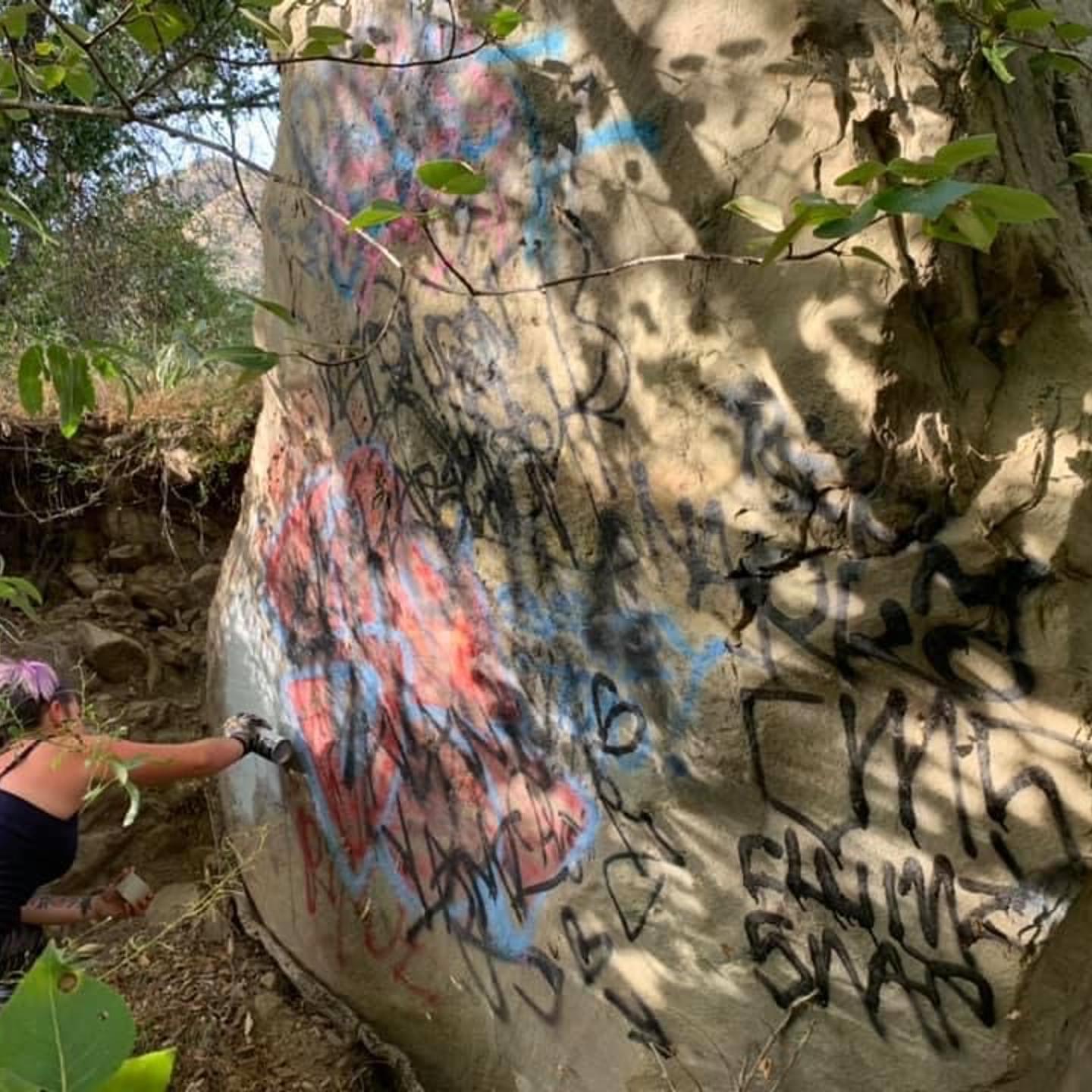 A volunteer works to remove graffiti from the Santa Paula Canyon in Ventura County, Calif.