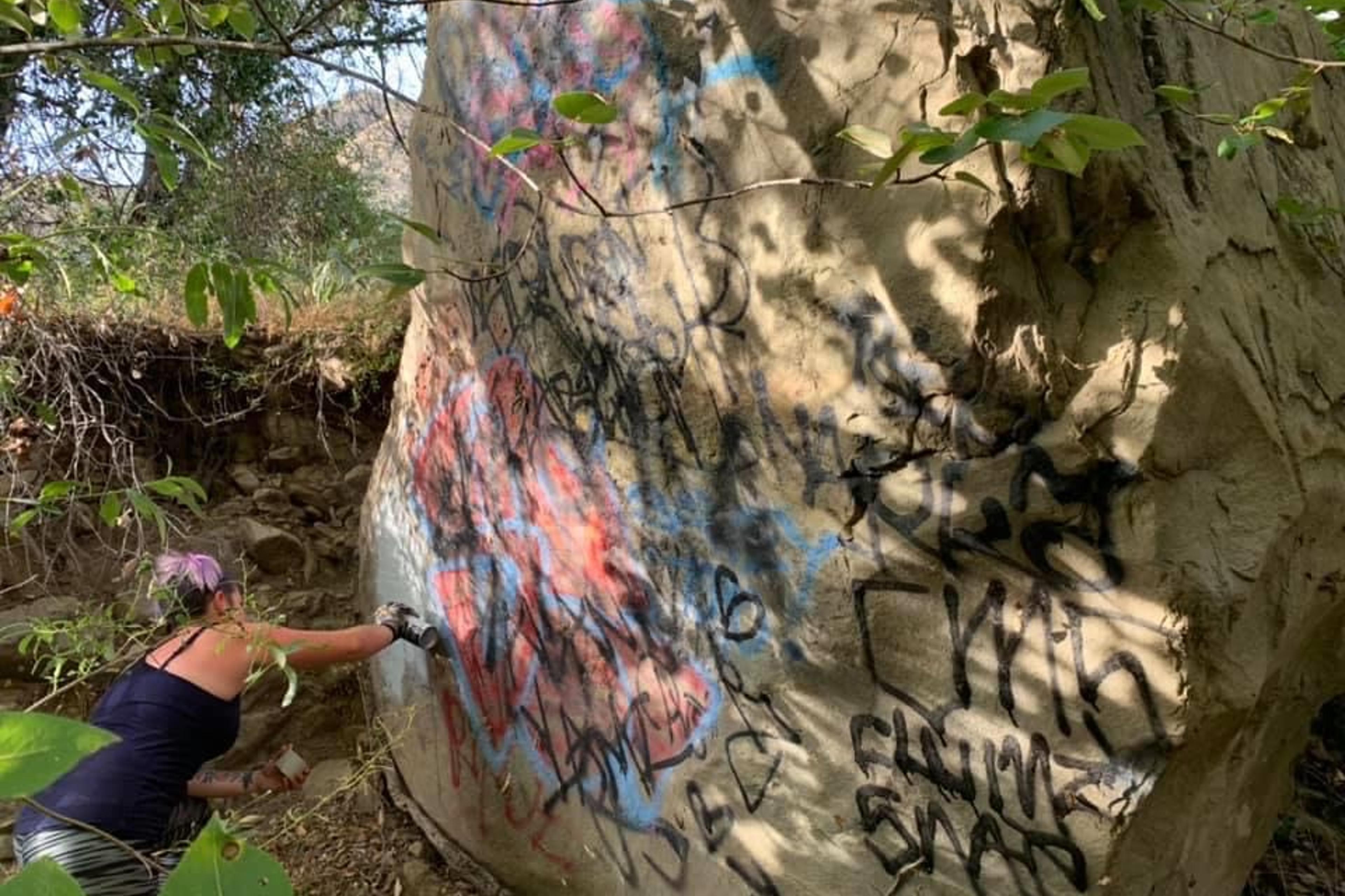 A volunteer works to remove graffiti from the Santa Paula Canyon in Ventura County, Calif.