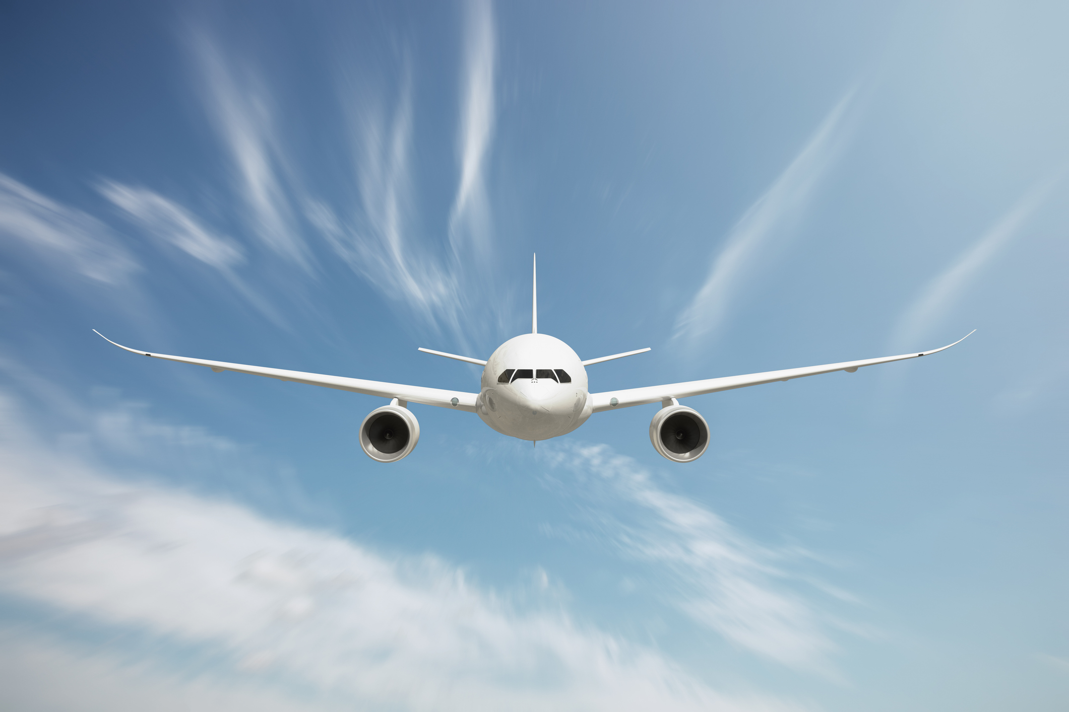 Front view of passenger airplane flying above clouds