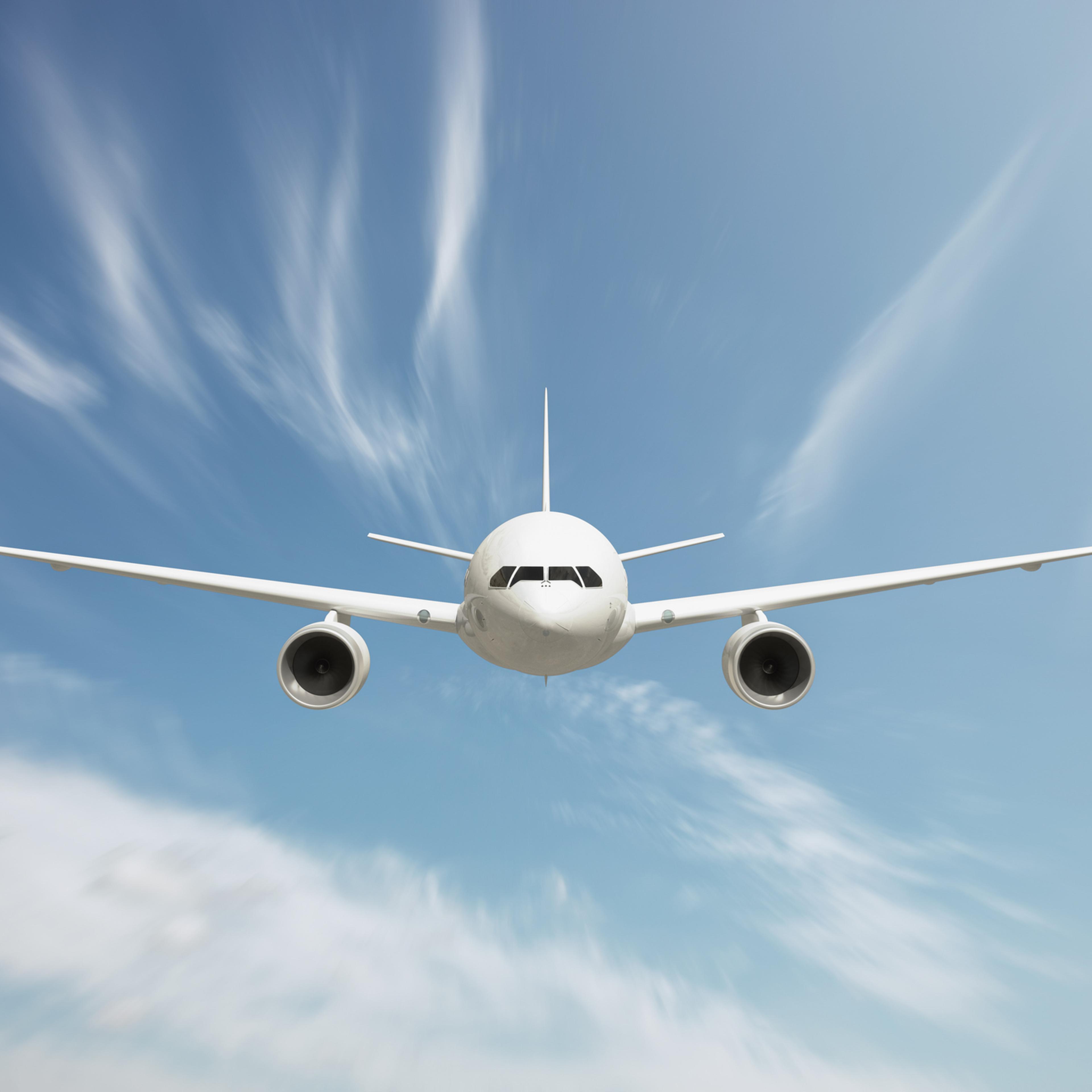 Front view of passenger airplane flying above clouds
