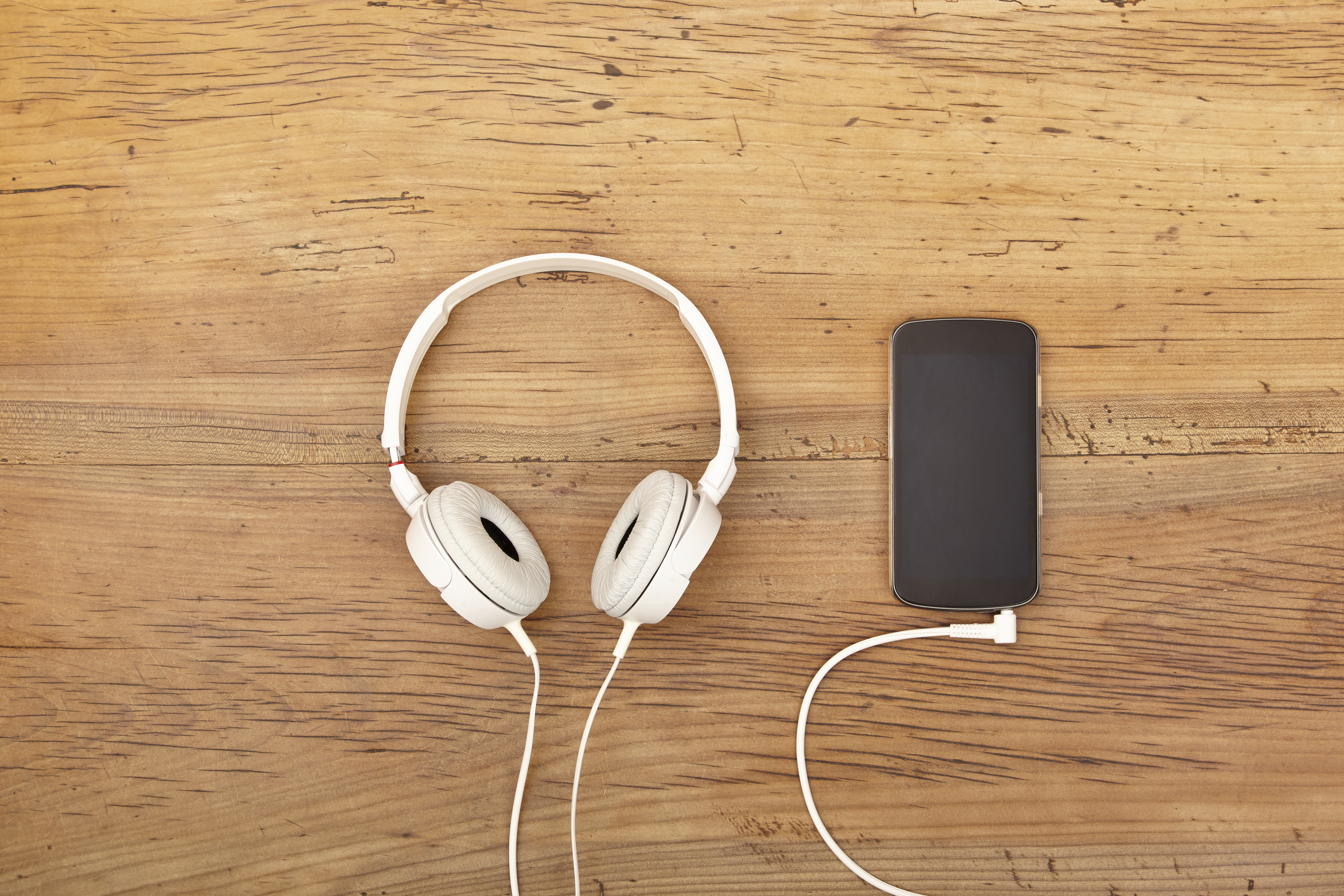 White headphones and smart phone on wood