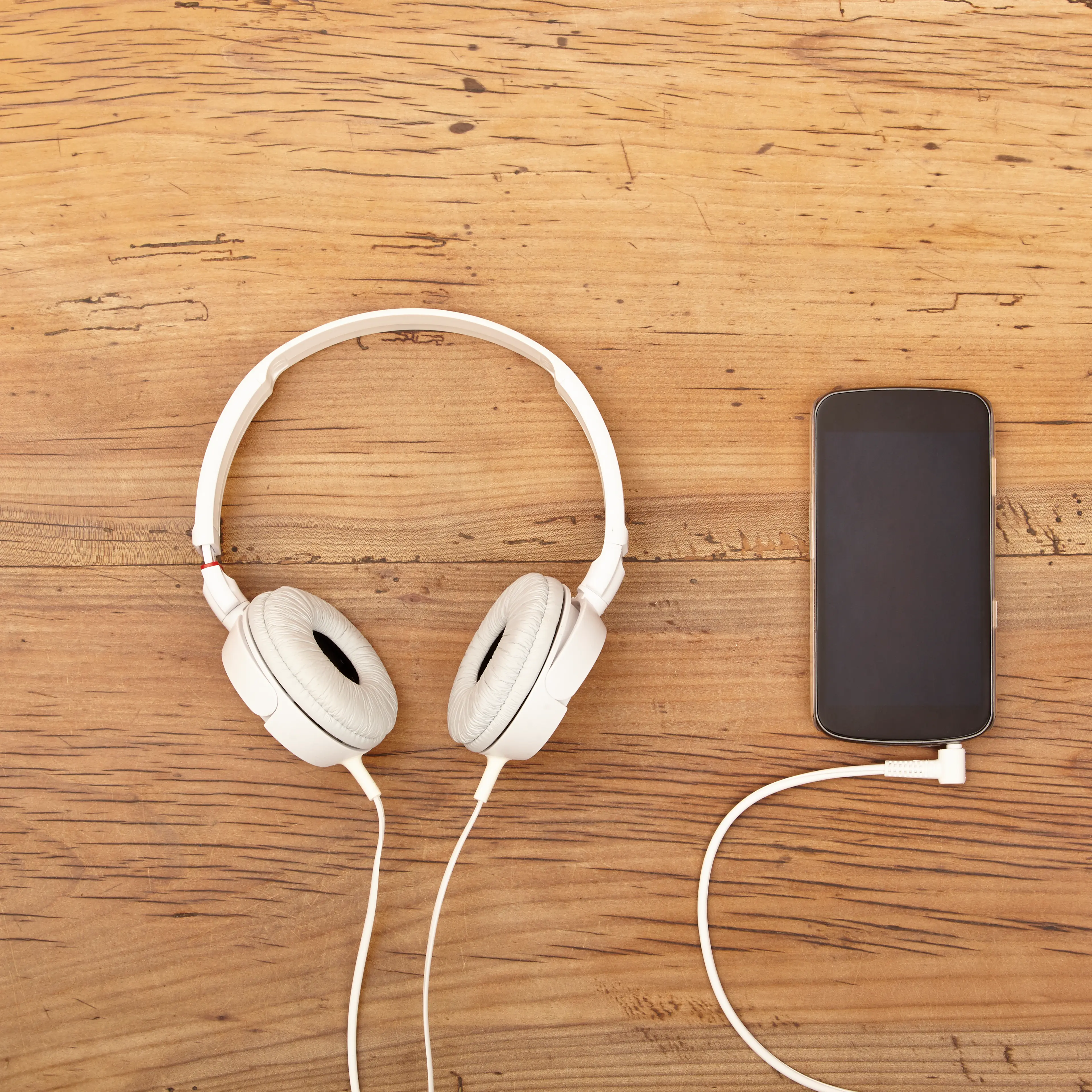 White headphones and smart phone on wood