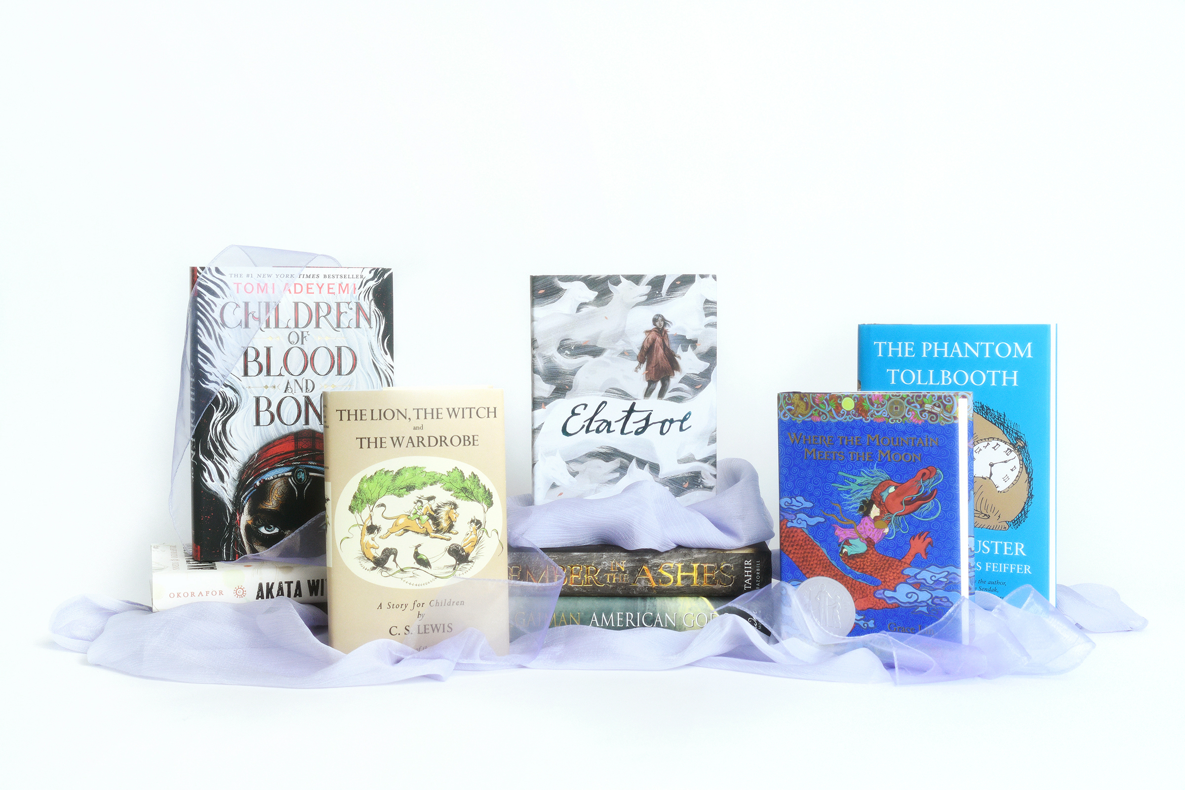 A collection of fantasy books surrounded by violet colored chiffon