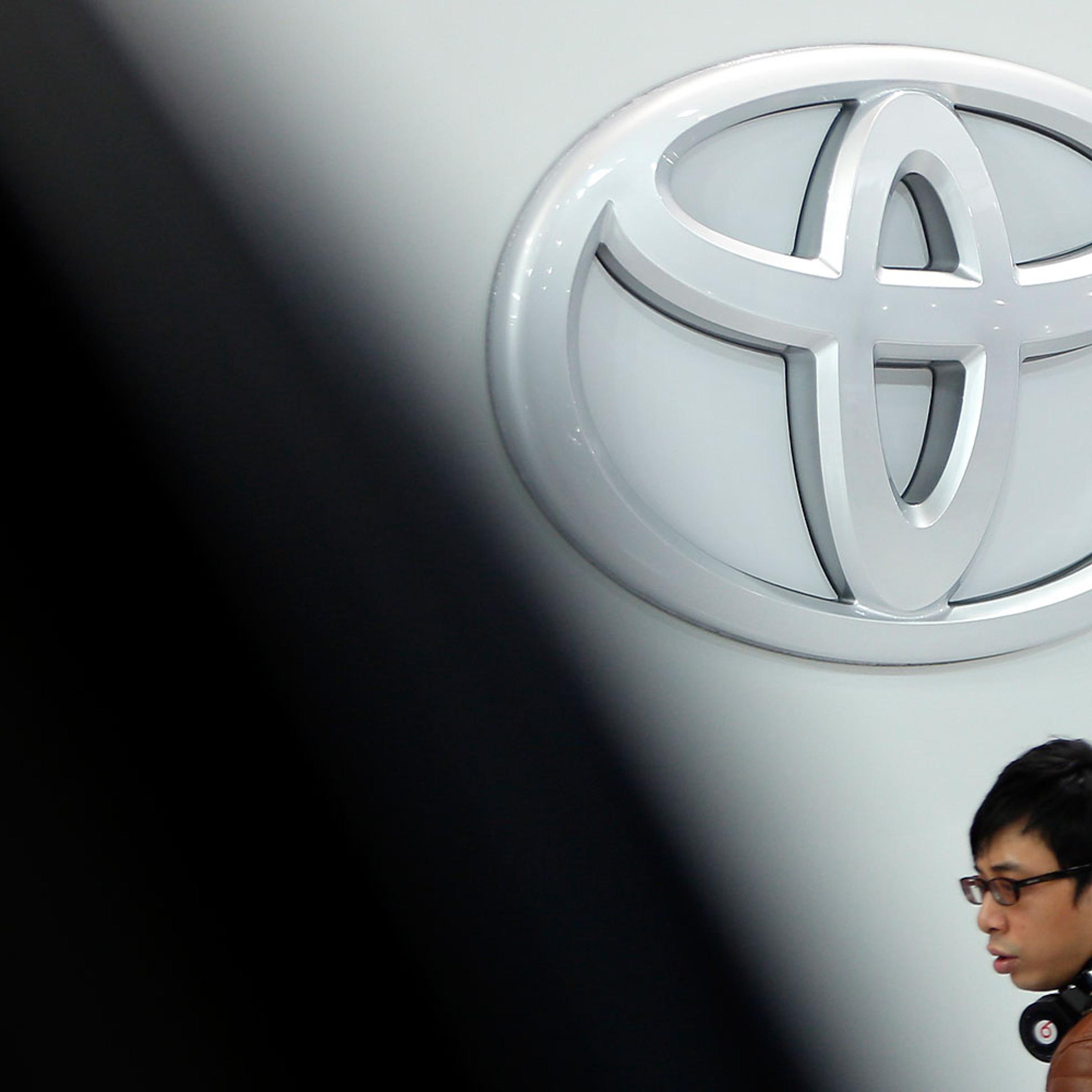 A visitor passes the Toyota Motor Corp. logo on display at the company's showroom in Tokyo, Japan, Feb. 12, 2014.