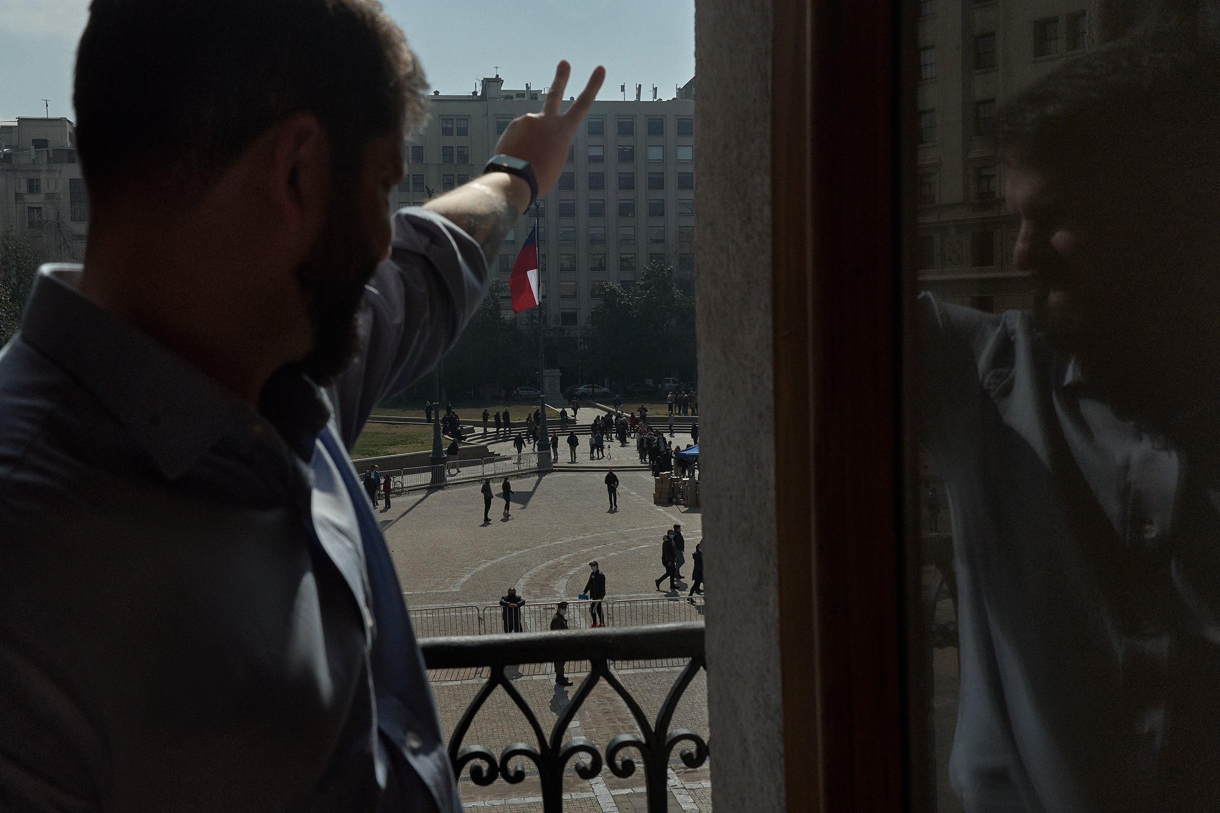 The president peeks out from the balcony of the presidential house, Palacio de la Moneda, Aug. 12—the same one he used for his speech on the day of his inauguration as president