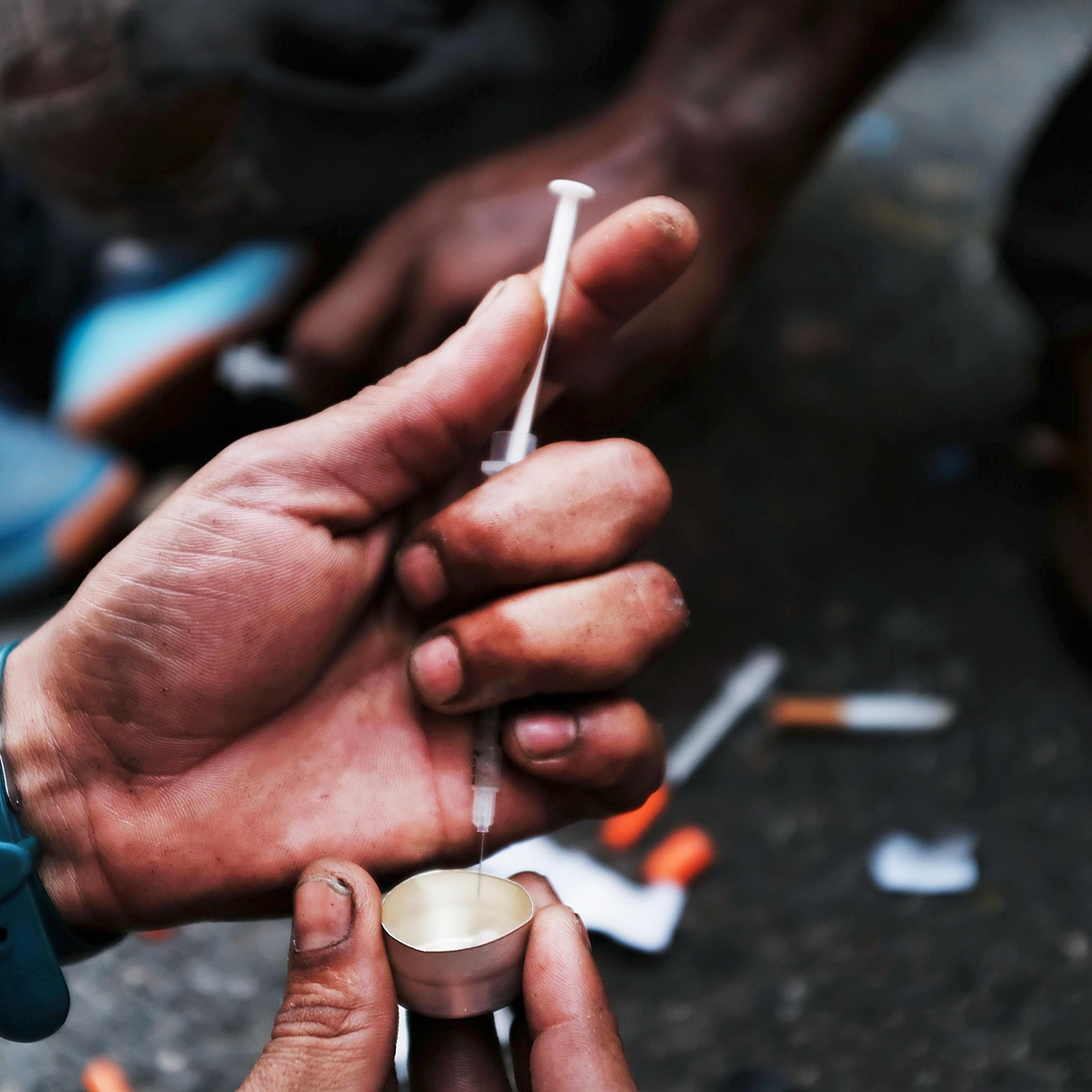 A user prepares to take heroin on a New York City street