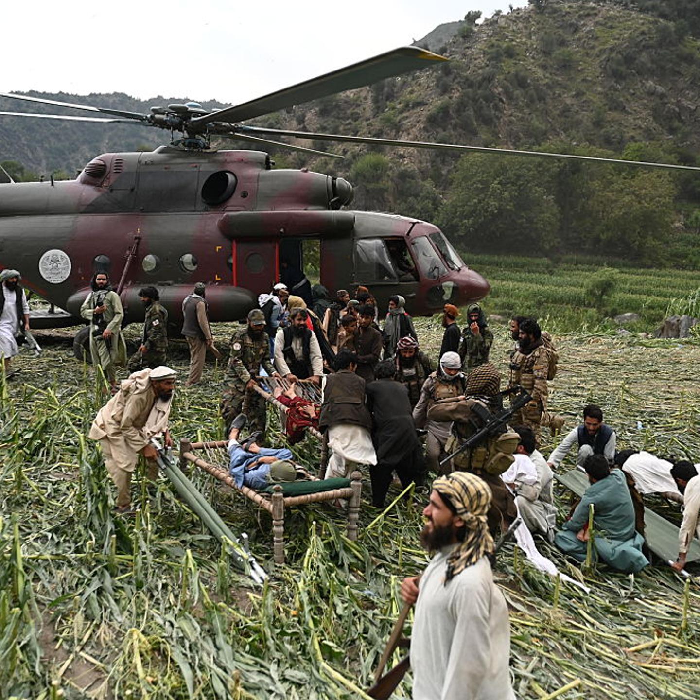Afghan volunteers and Taliban security personnel work to move injured people near a military helicopter following earthquakes in the Mazar Dara village of Nurgal, a district of the Kunar Province, in Eastern Afghanistan, on Sept. 1, 2025.