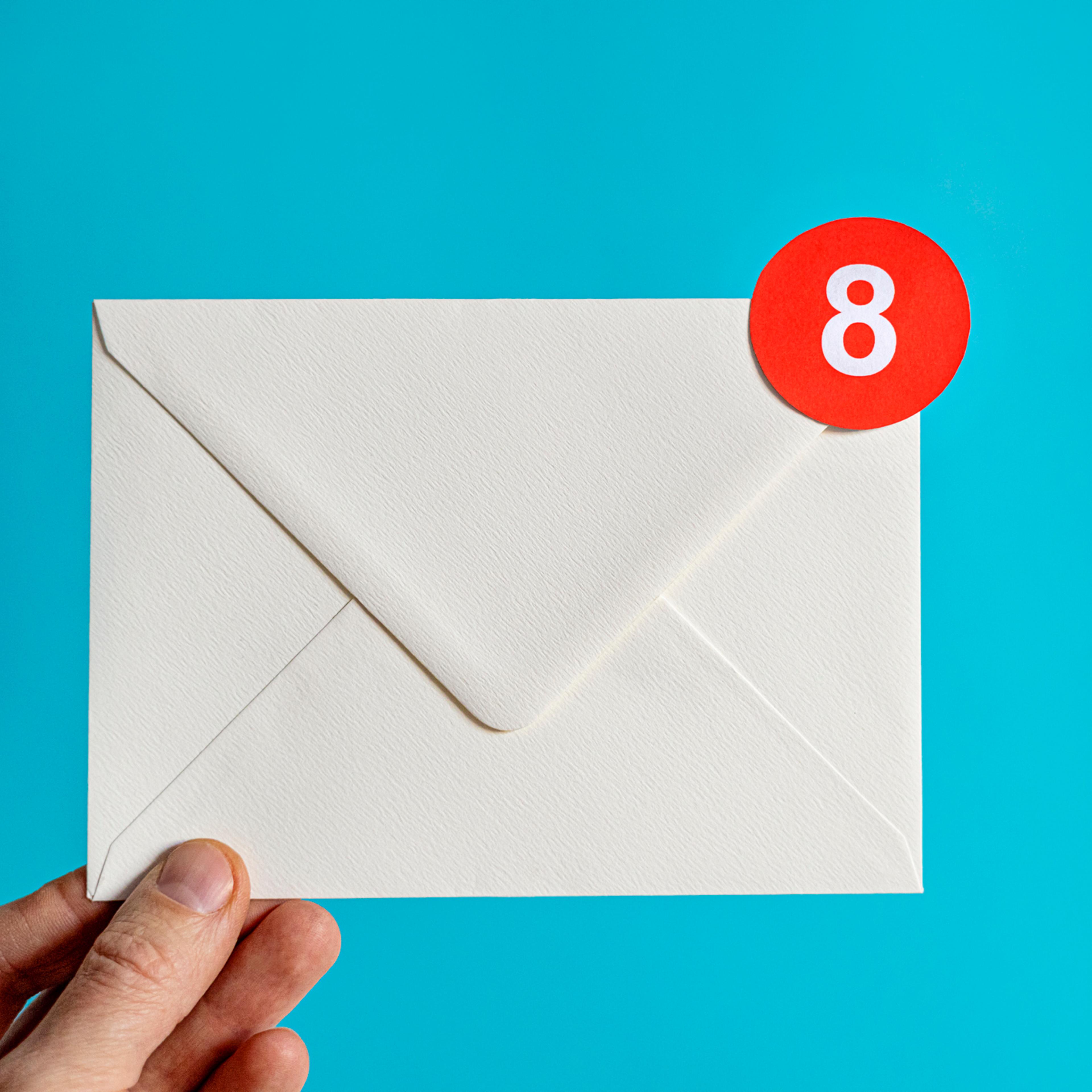 Hand holding white envelope with notification bubble
