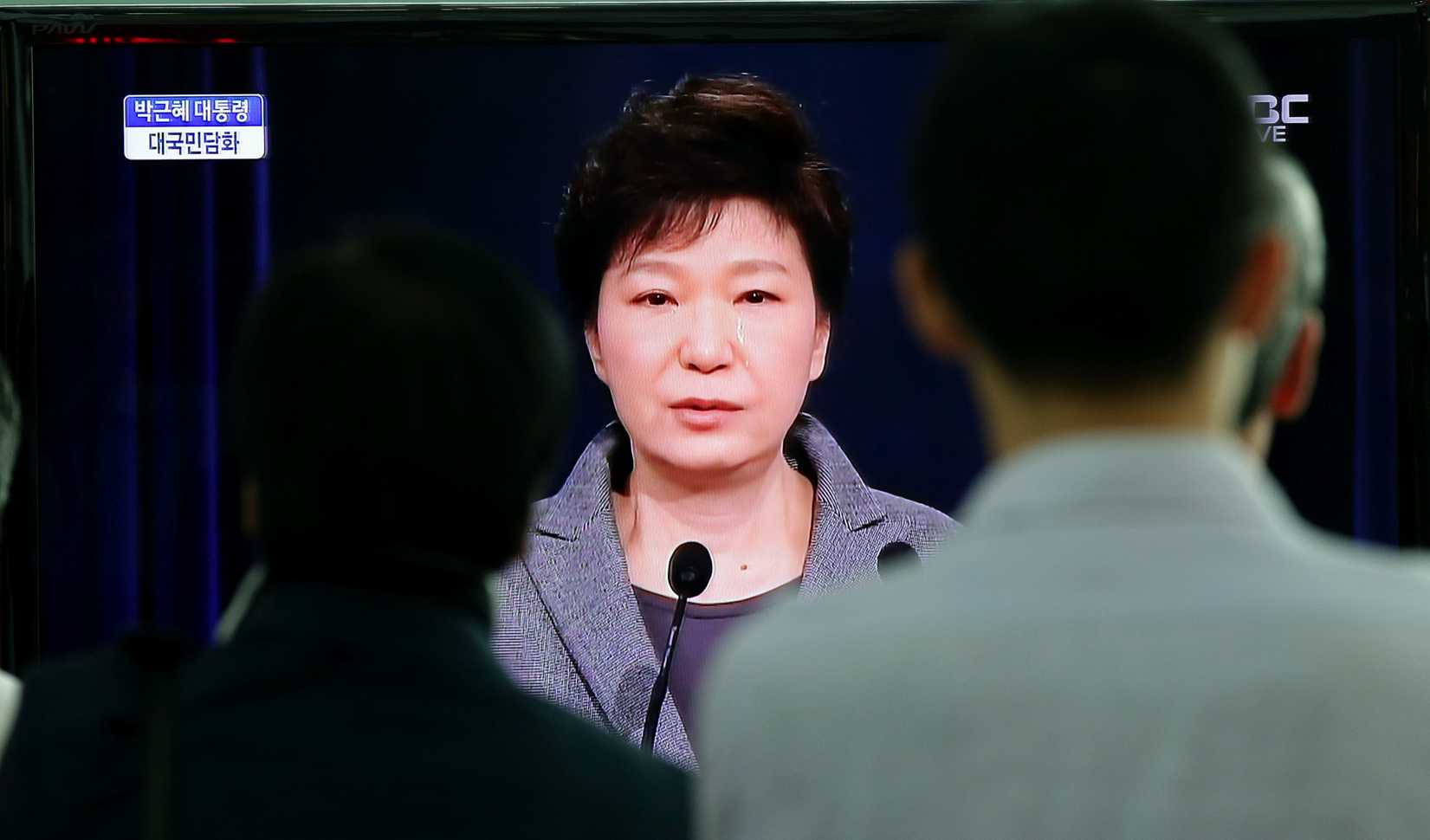 Passersby at a Seoul train station watch a live television broadcast of South Korean President Park Geun-hye's speech to the nation on the <i>Sewol</i> ferry tragedy on May 19, 2014 