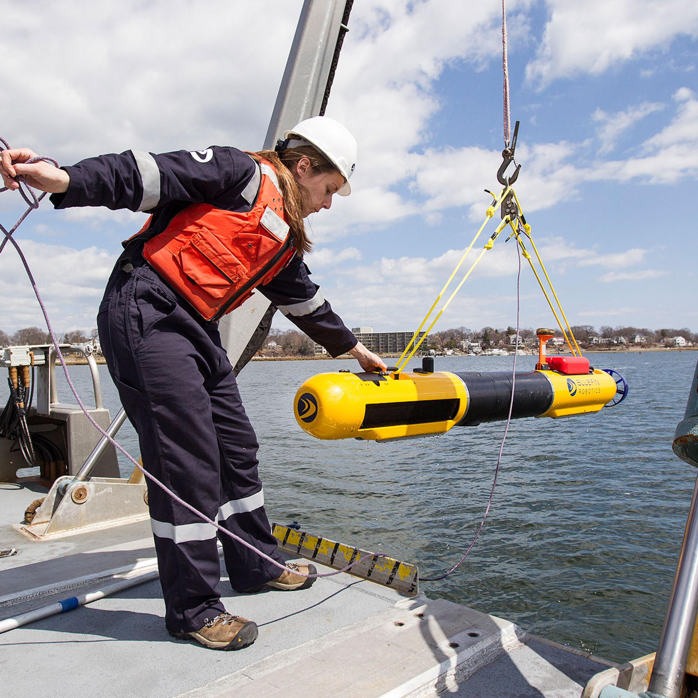 A submarine built by Bluefin Robotics is lowered into the water by a systems engineer in Quincy, Mass., April 9, 2014