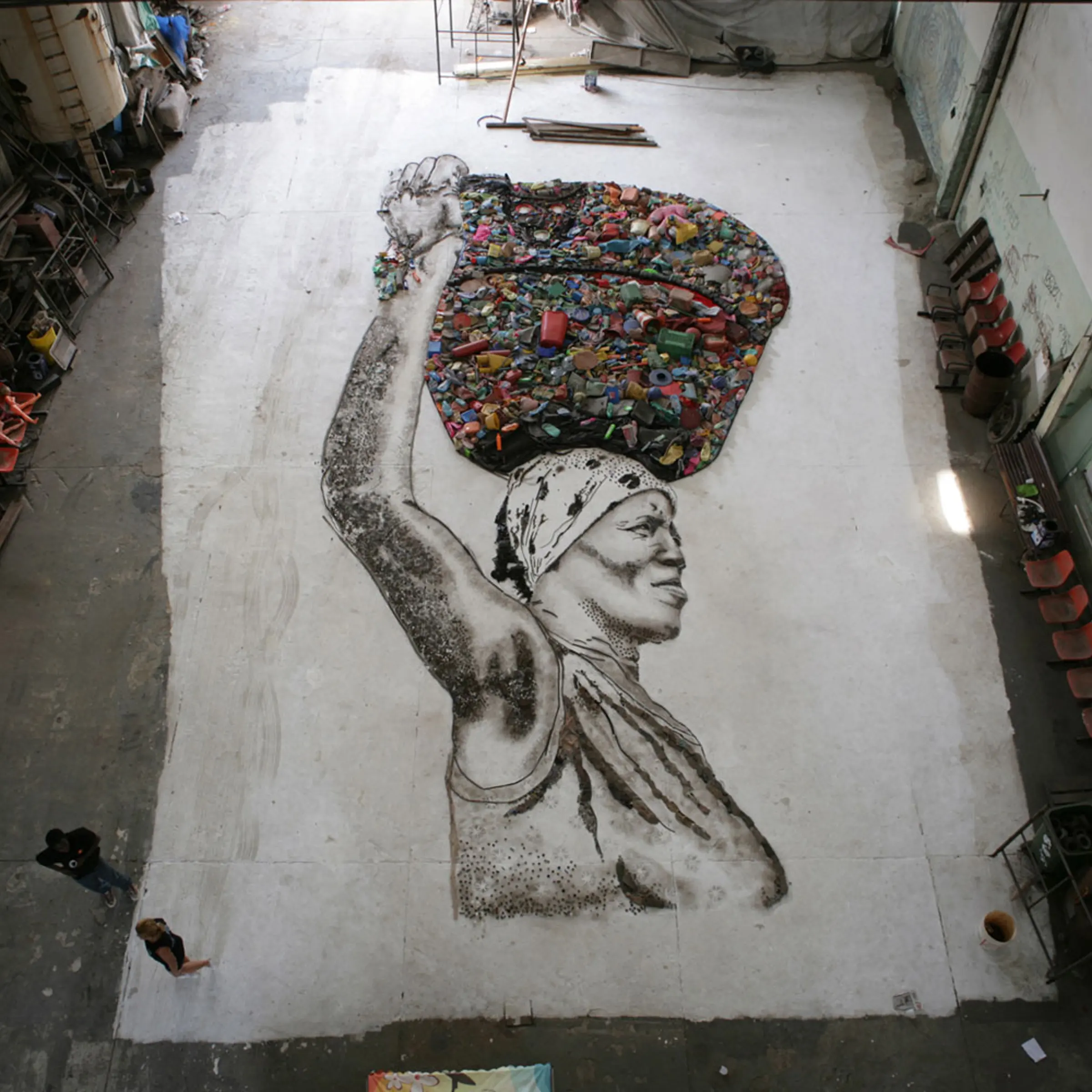 The portrait of Irma is created on the floor of the studio by Muniz and the workers of Jardim Gramacho. Once complete, the final portrait will be photographed from above by Muniz