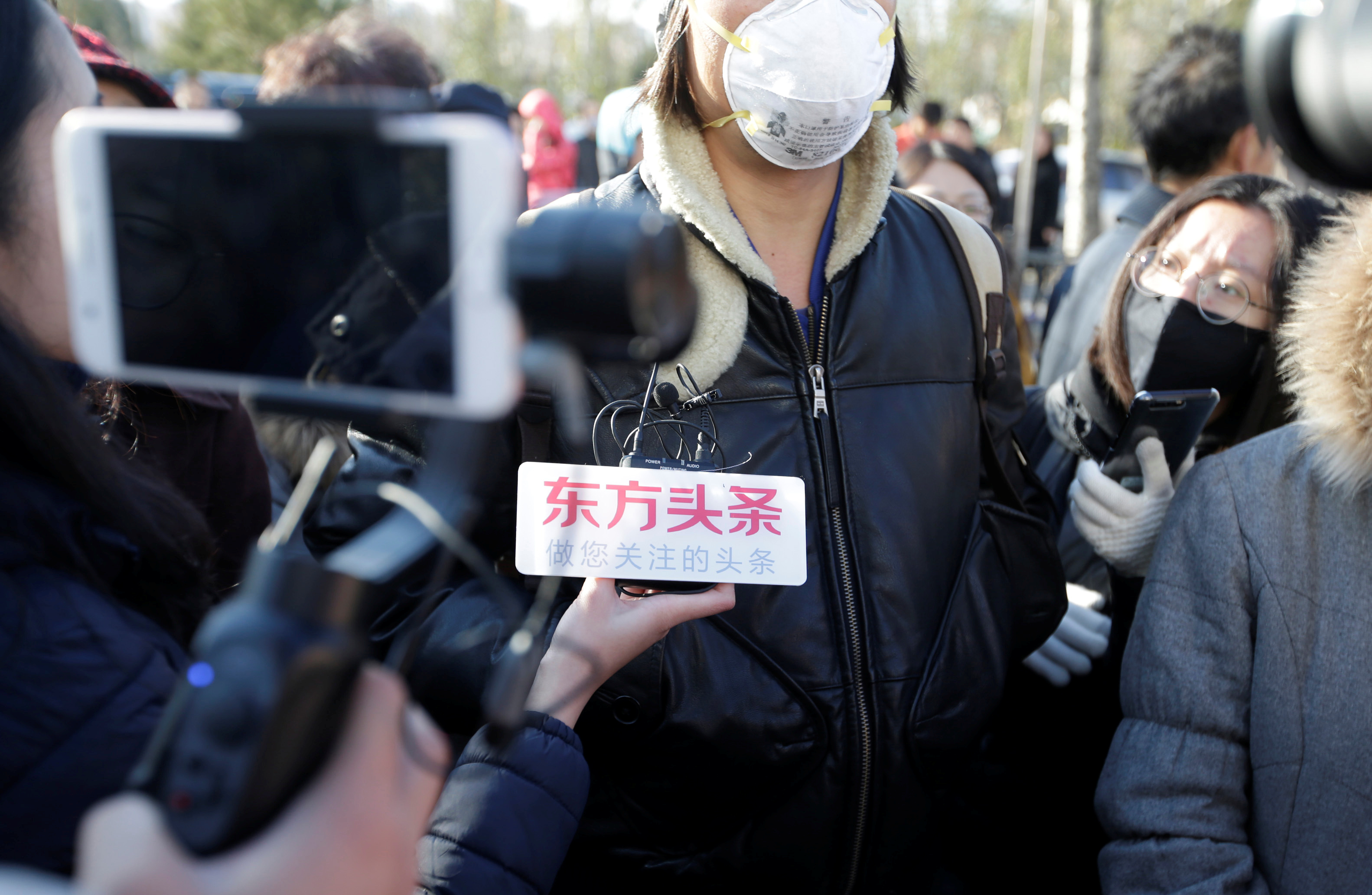 Parent is surrounded by members of the media outside the kindergarten run by pre-school operator RYB Education Inc