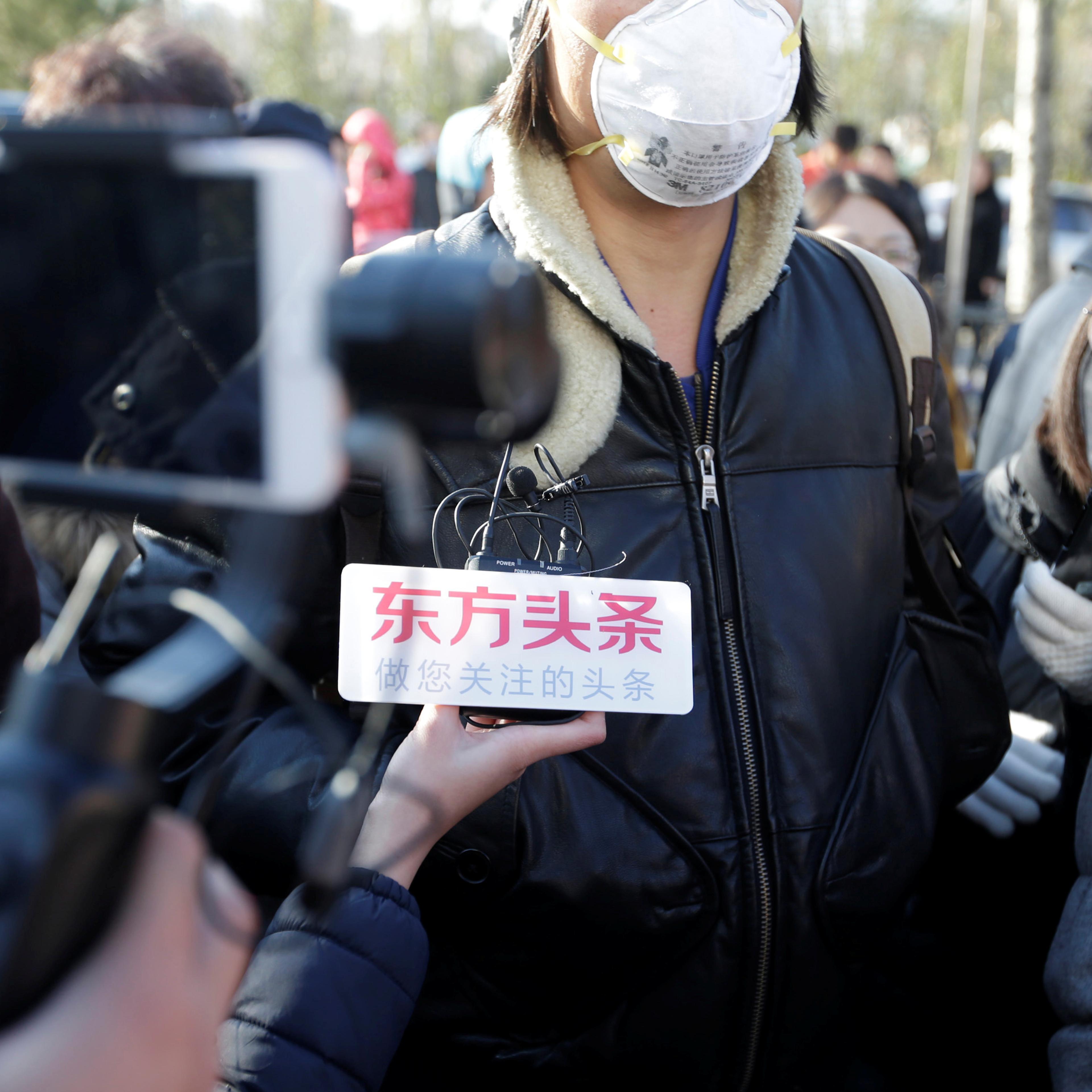 Parent is surrounded by members of the media outside the kindergarten run by pre-school operator RYB Education Inc