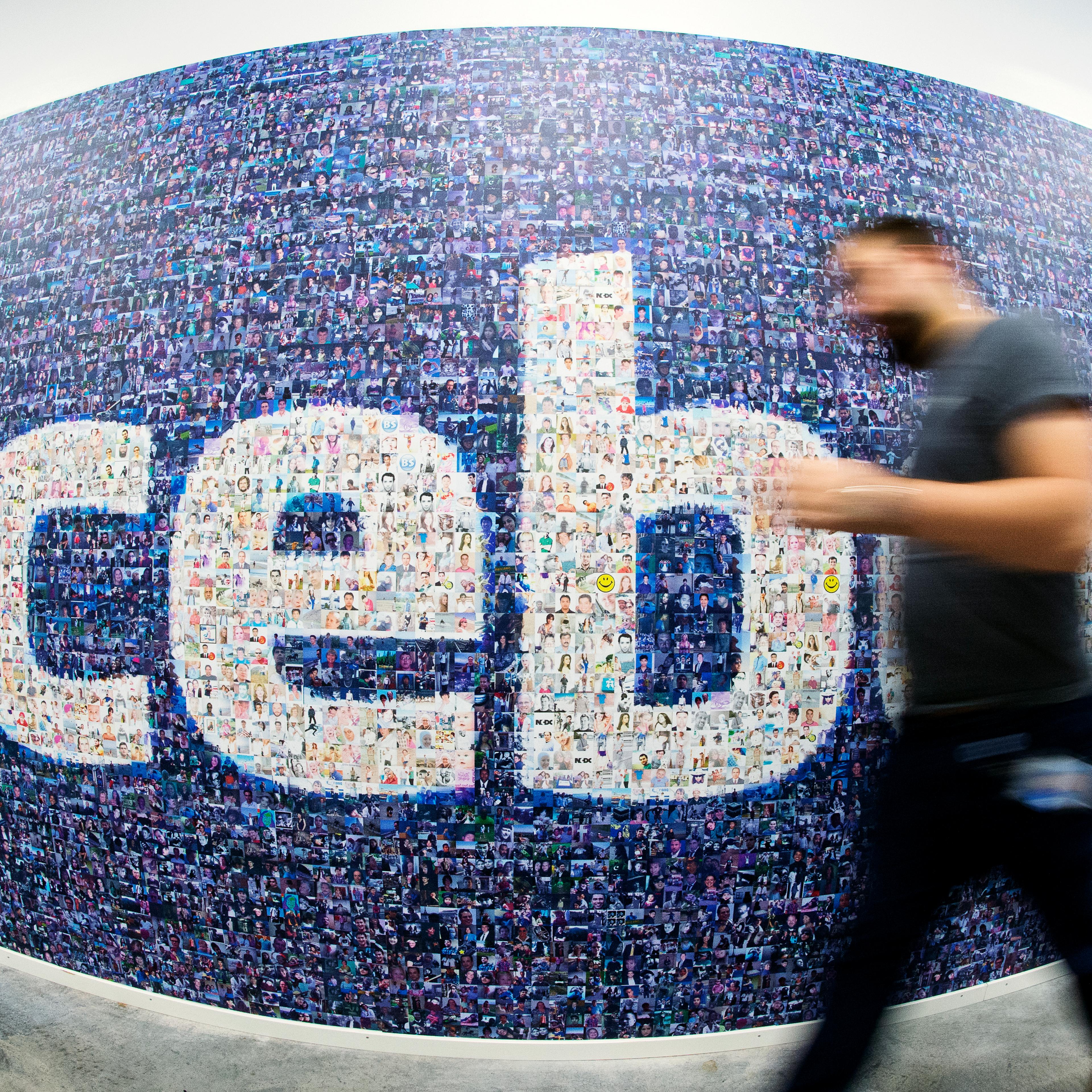 This picture taken with a fisheye lens shows a man walk past a big logo created from pictures of Facebook users worldwide in the company's Data Center, its first outside the US on November 7, 2013 in Lulea, in Swedish Lapland.