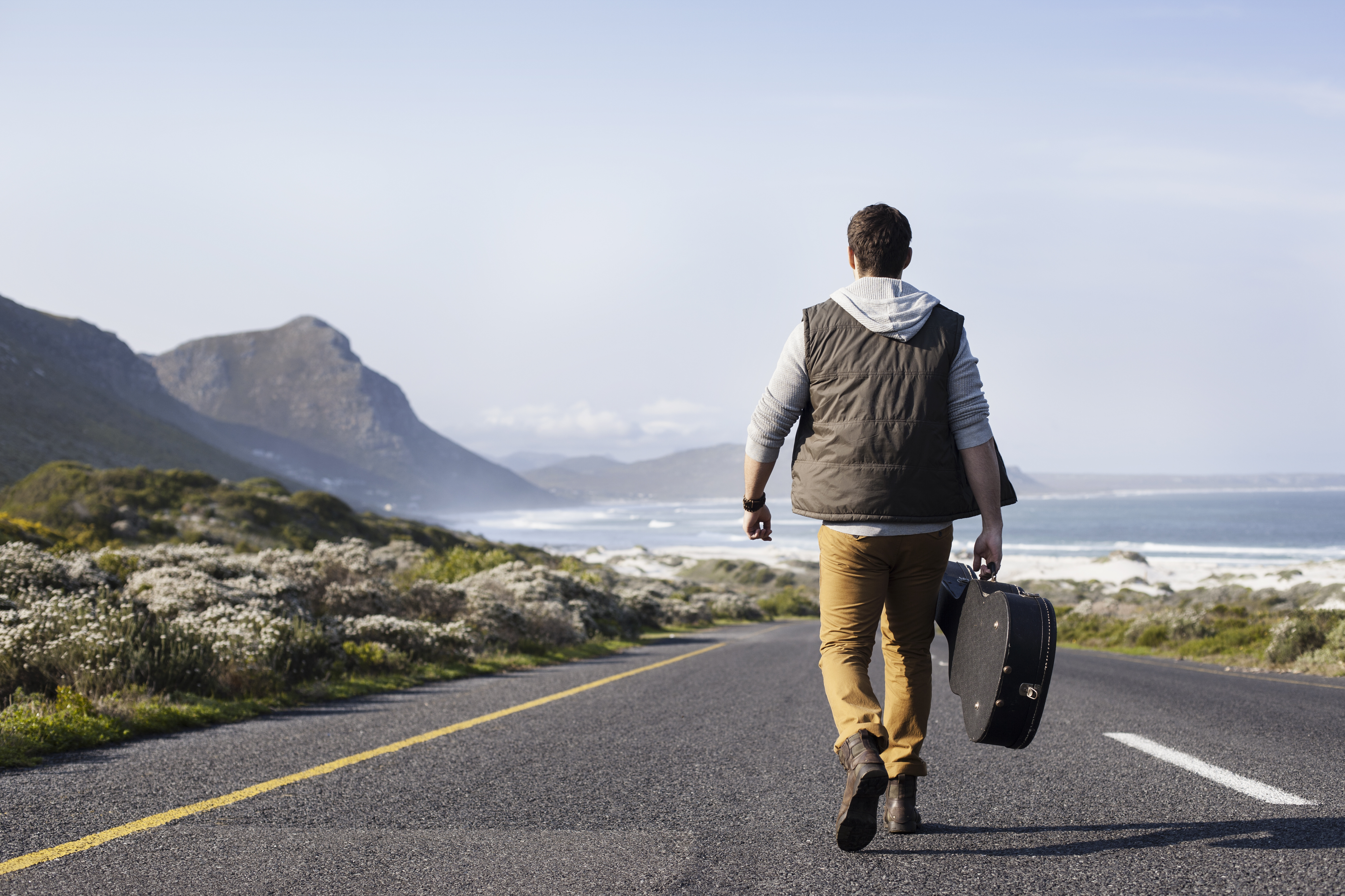 man-walking-road-guitar-rear-view