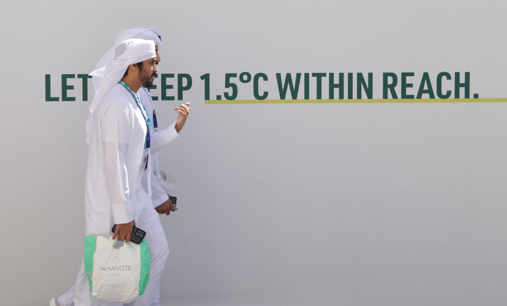 People walk past the slogan: "Let's Keep 1.5 Degrees Celsius Within Reach" prior to the opening ceremony of the UNFCCC COP28 Climate Conference on Nov. 30, 2023 in Dubai, United Arab Emirates.