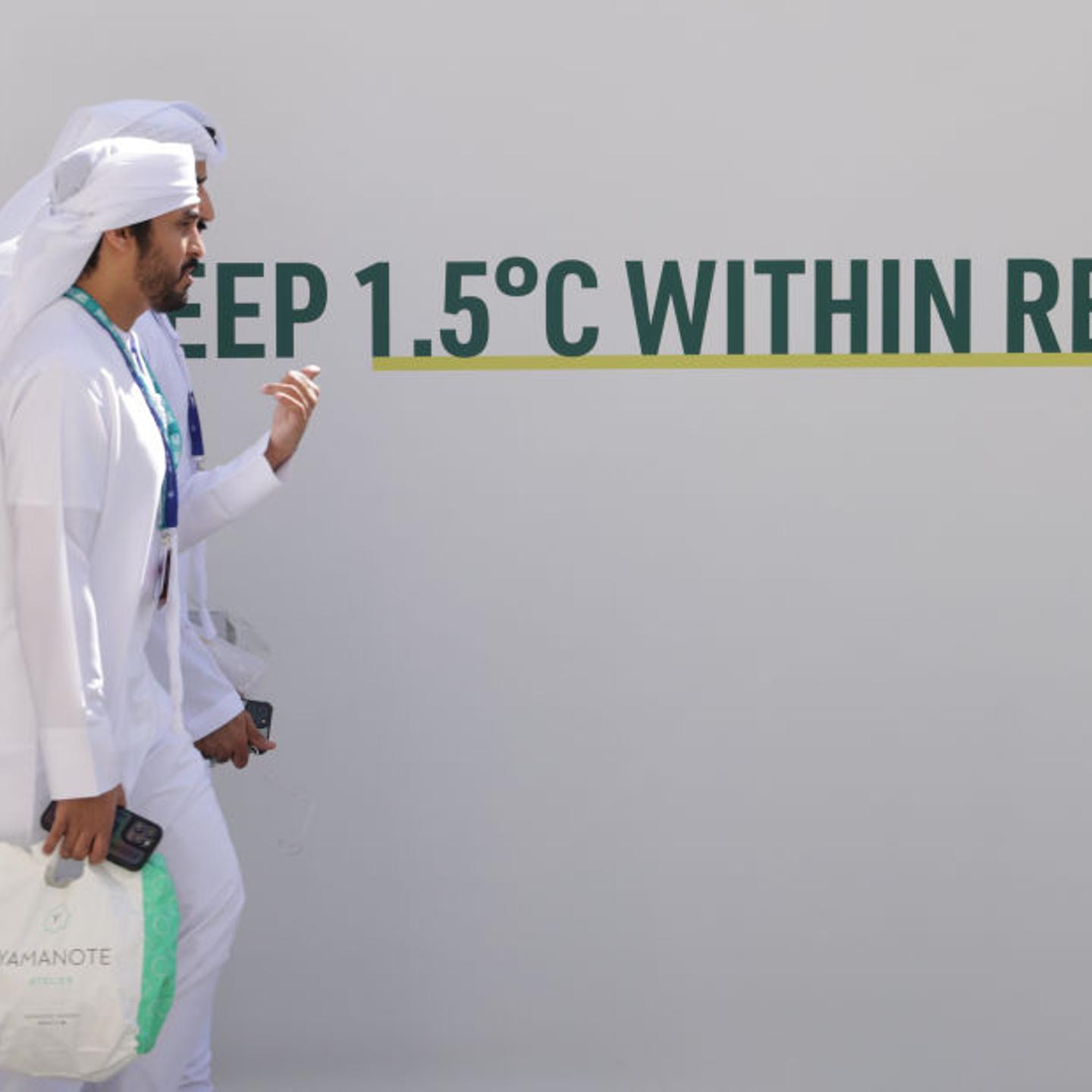People walk past the slogan: "Let's Keep 1.5 Degrees Celsius Within Reach" prior to the opening ceremony of the UNFCCC COP28 Climate Conference on Nov. 30, 2023 in Dubai, United Arab Emirates.