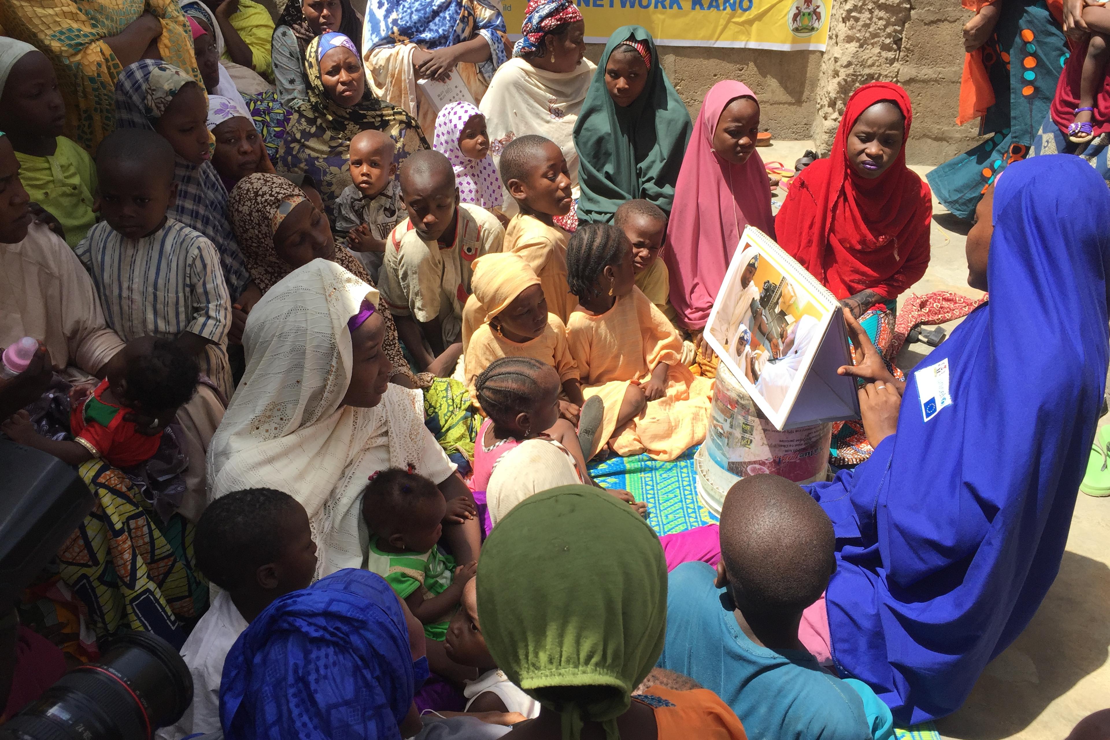 A health care worker from UNICEF and the Bill and Melinda Gates Foundation teaches polio vaccination protocols during a naming ceremony in Kano, Nigeria.