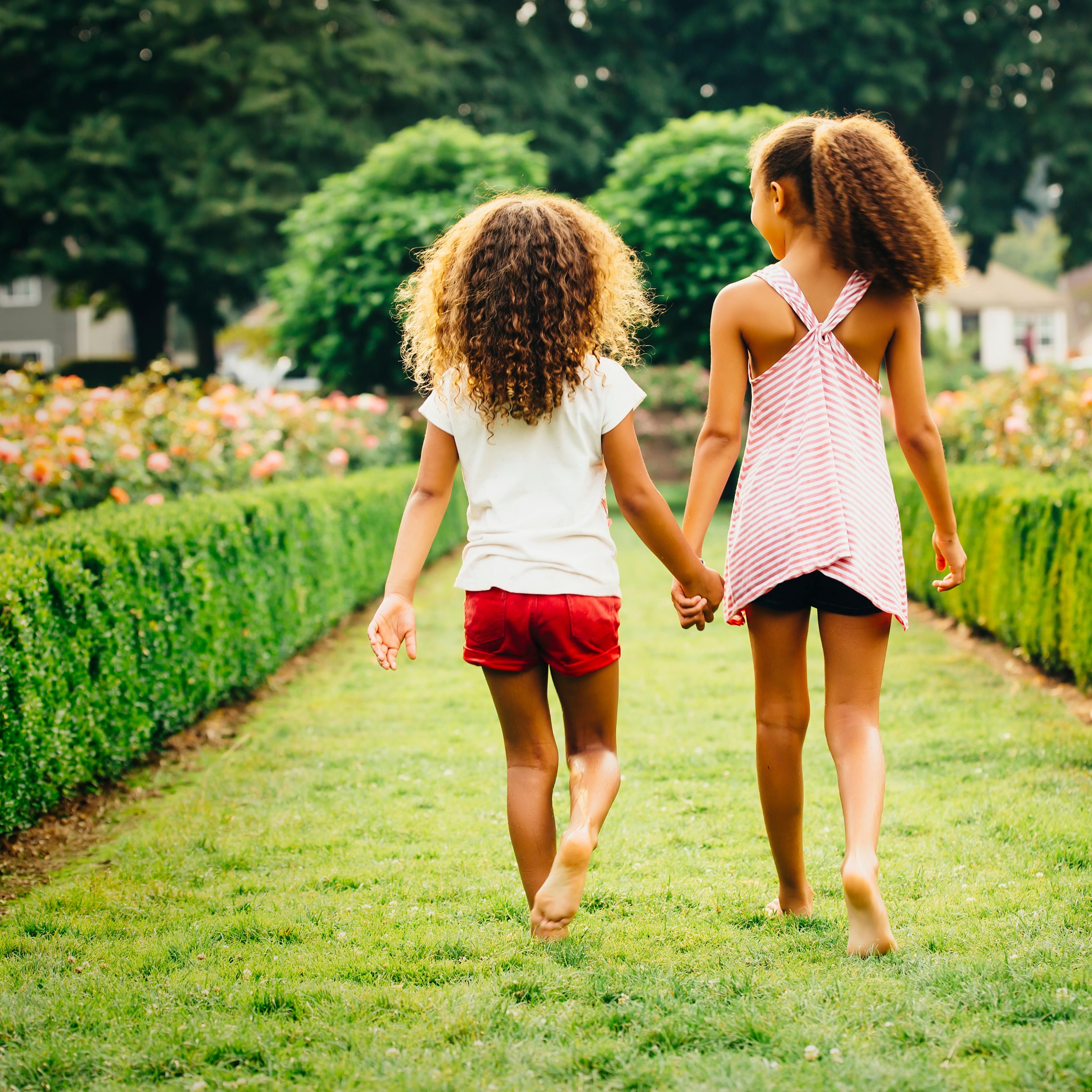 sisters-walking-garden-rear-view