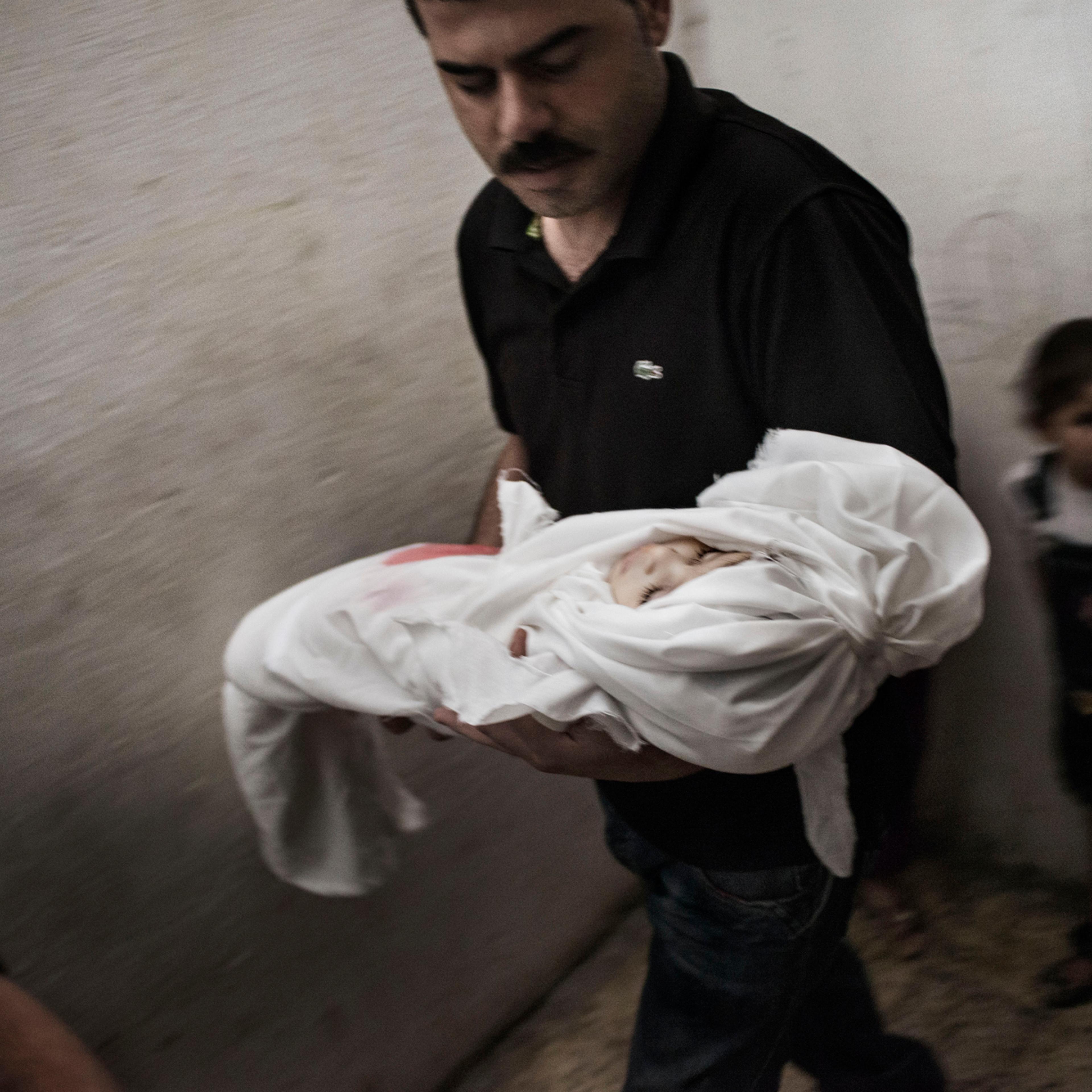 The father of 18-month-old Razel Netzlream, who was fatally wounded during an airstrike, carries her body right before her funeral, in Rafah, Gaza Strip, July 18, 2014.