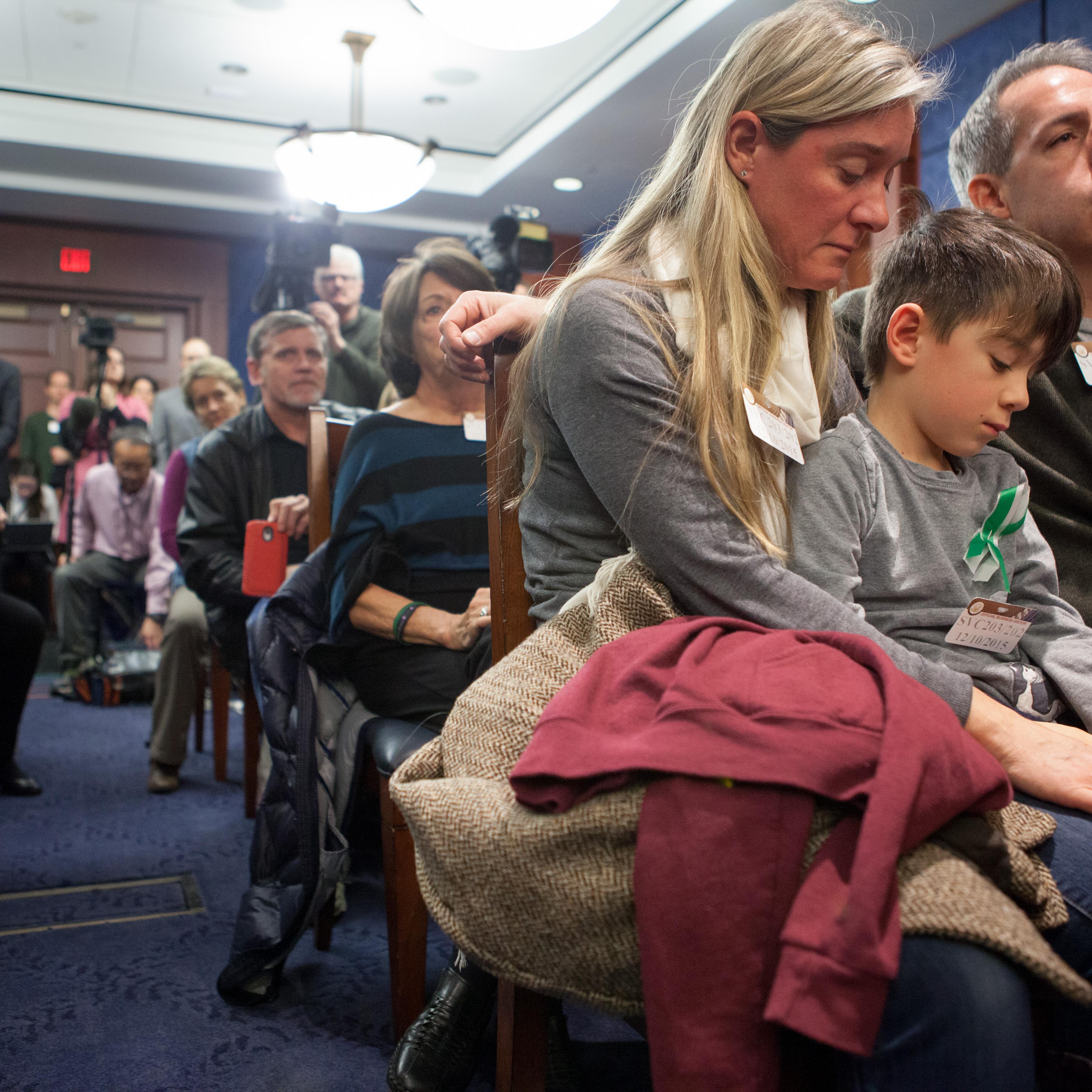 Rafe D'Agostino, 7, a second grader, sits between his parents Noelle and Paul D'Agostino during a press conference on Capitol Hill on Dec. 10.