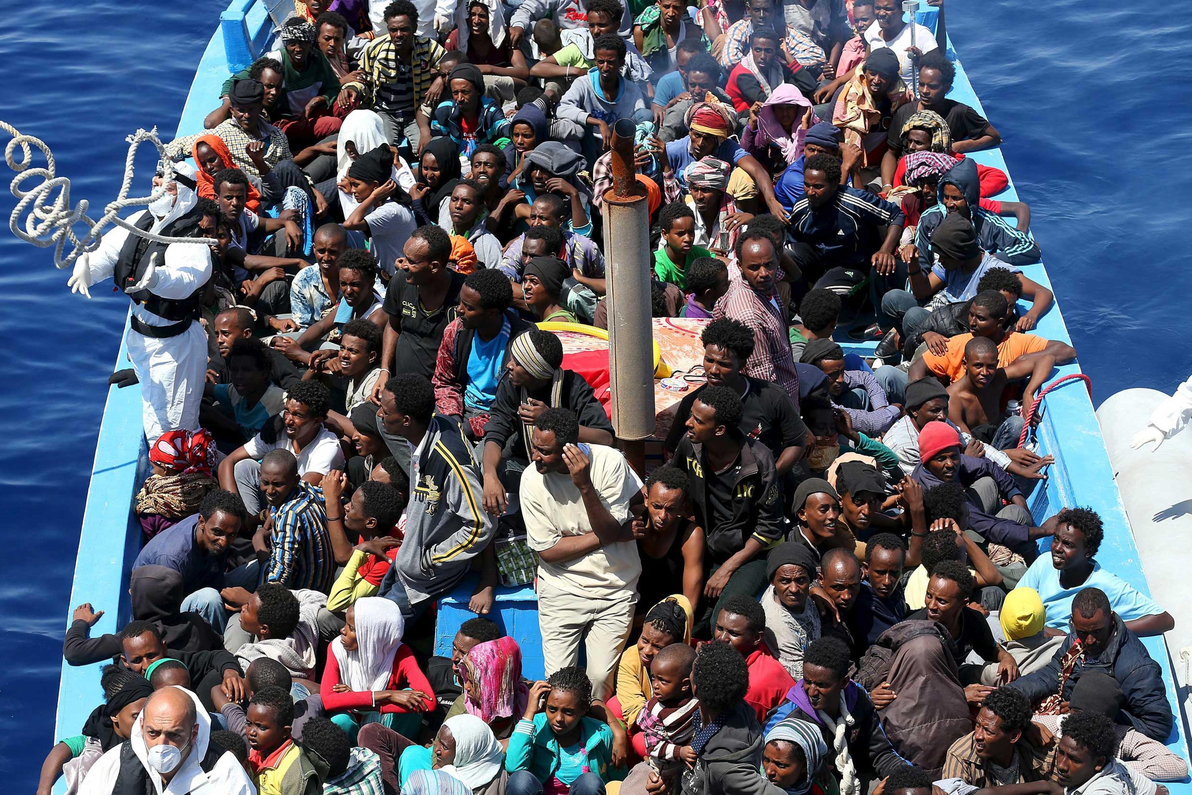 A group of 300 sub-Saharan African migrants sit on board a boat during a rescue operation off the coast of Sicily, Italy on May 14, 2015.