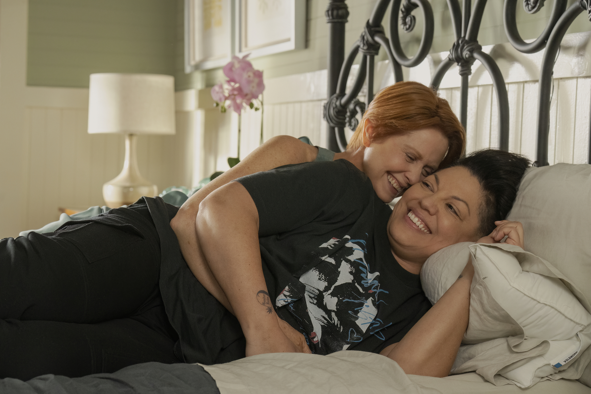 Cynthia Nixon and Sara Ramírez laying in bed together.