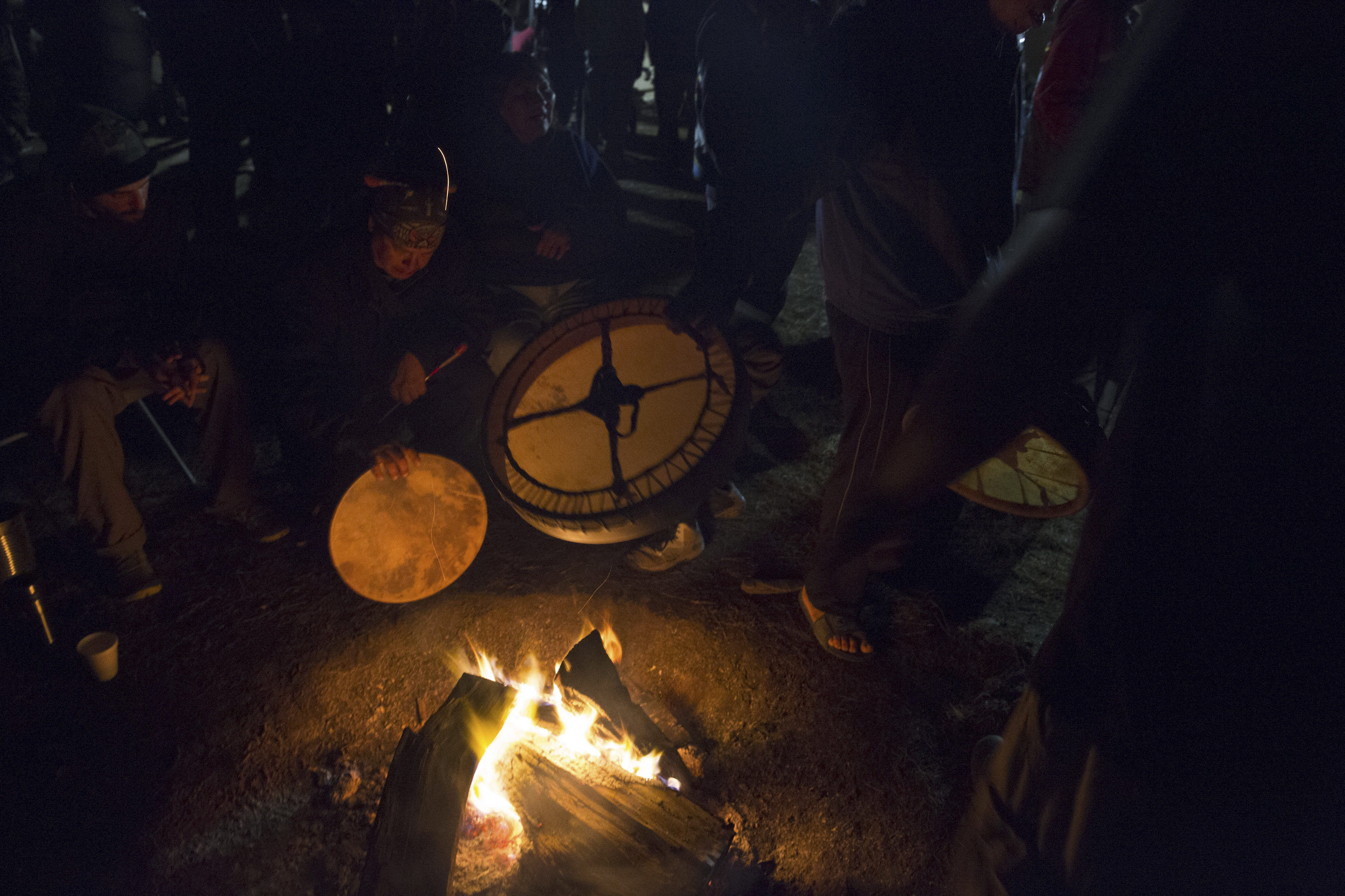 Drummers warm up their instruments over the fire Sacred Stone Camp, North Dakota on Sept. 8, 2016.