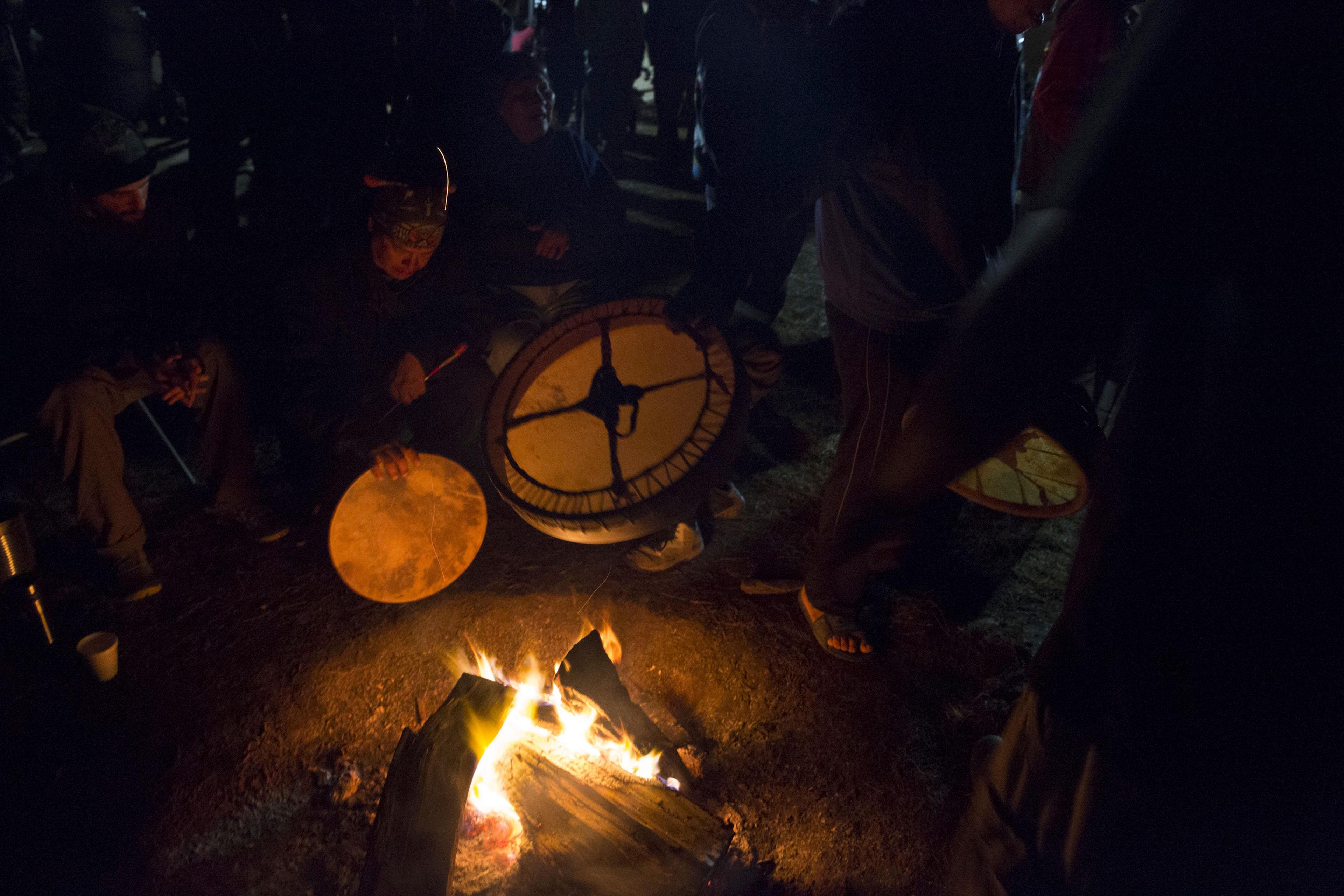 Drummers warm up their instruments over the fire Sacred Stone Camp, North Dakota on Sept. 8, 2016.