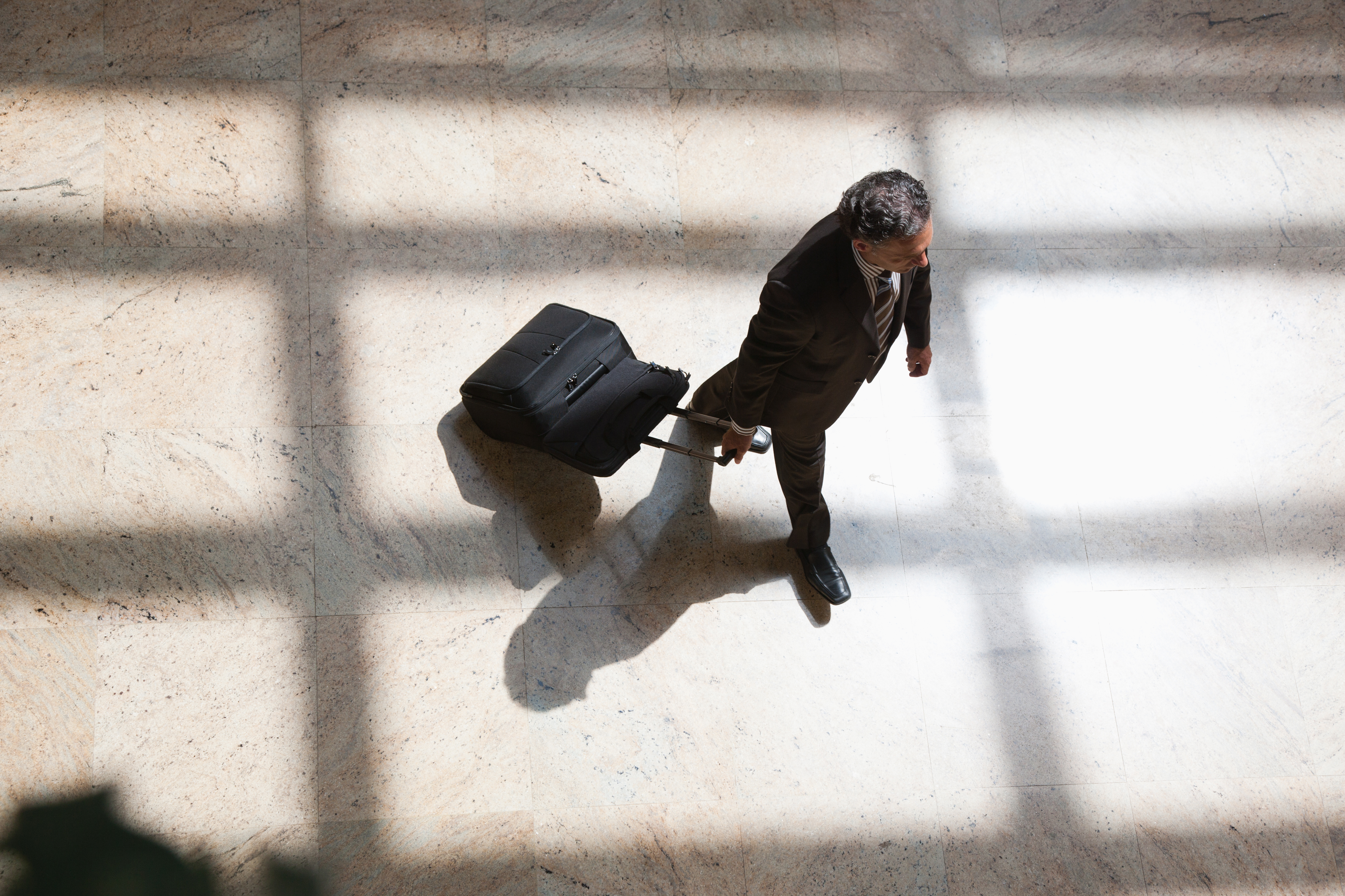 Businessman pulling rolling suitcase
